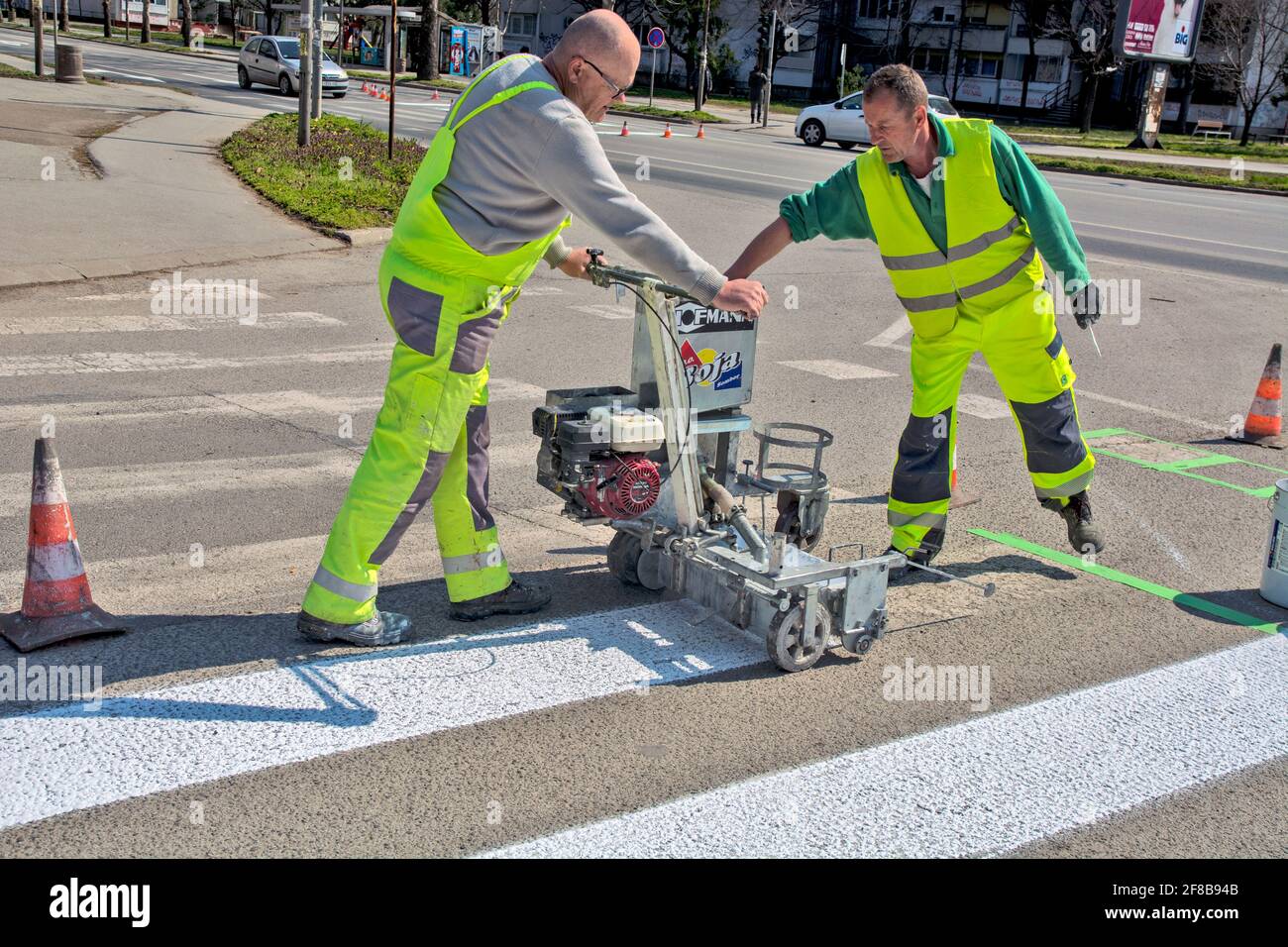 Zrenjanin, Serbie le 26 mars 2021. Les travailleurs d'une entreprise qui peint des passages piétons, communément appelés « zèbres », marquent et peignent sur l'asphalte. Banque D'Images