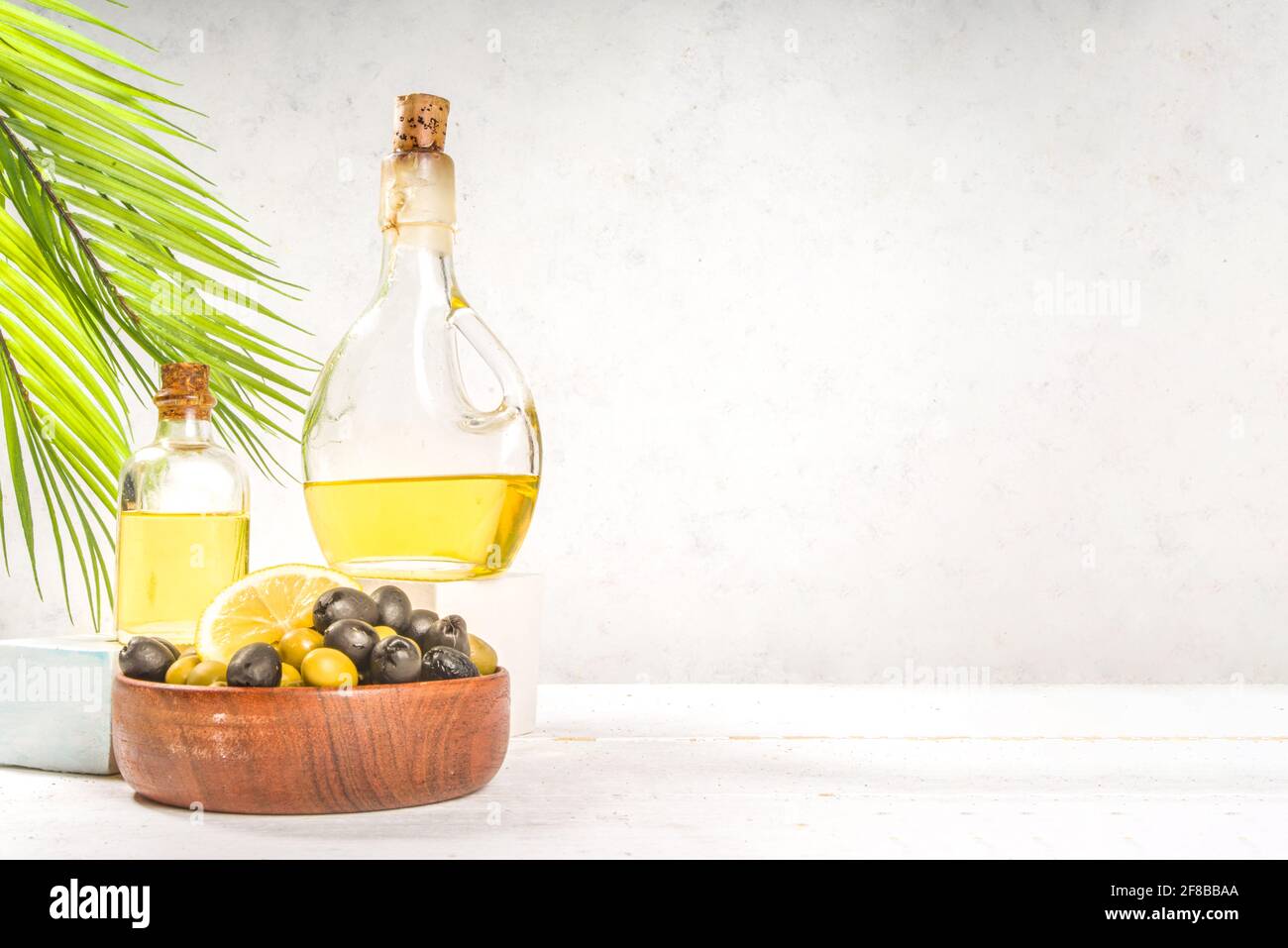 Cuisine méditerranéenne traditionnelle. Olives vertes et noires avec bouteilles d'huile d'olive sur fond de bois blanc Banque D'Images