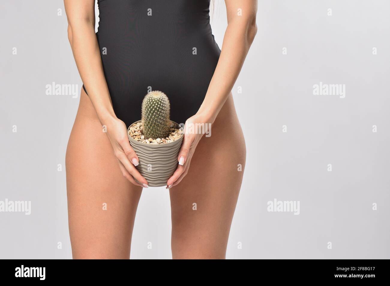Femme tenant un cactus dans une zone de bikini Banque D'Images