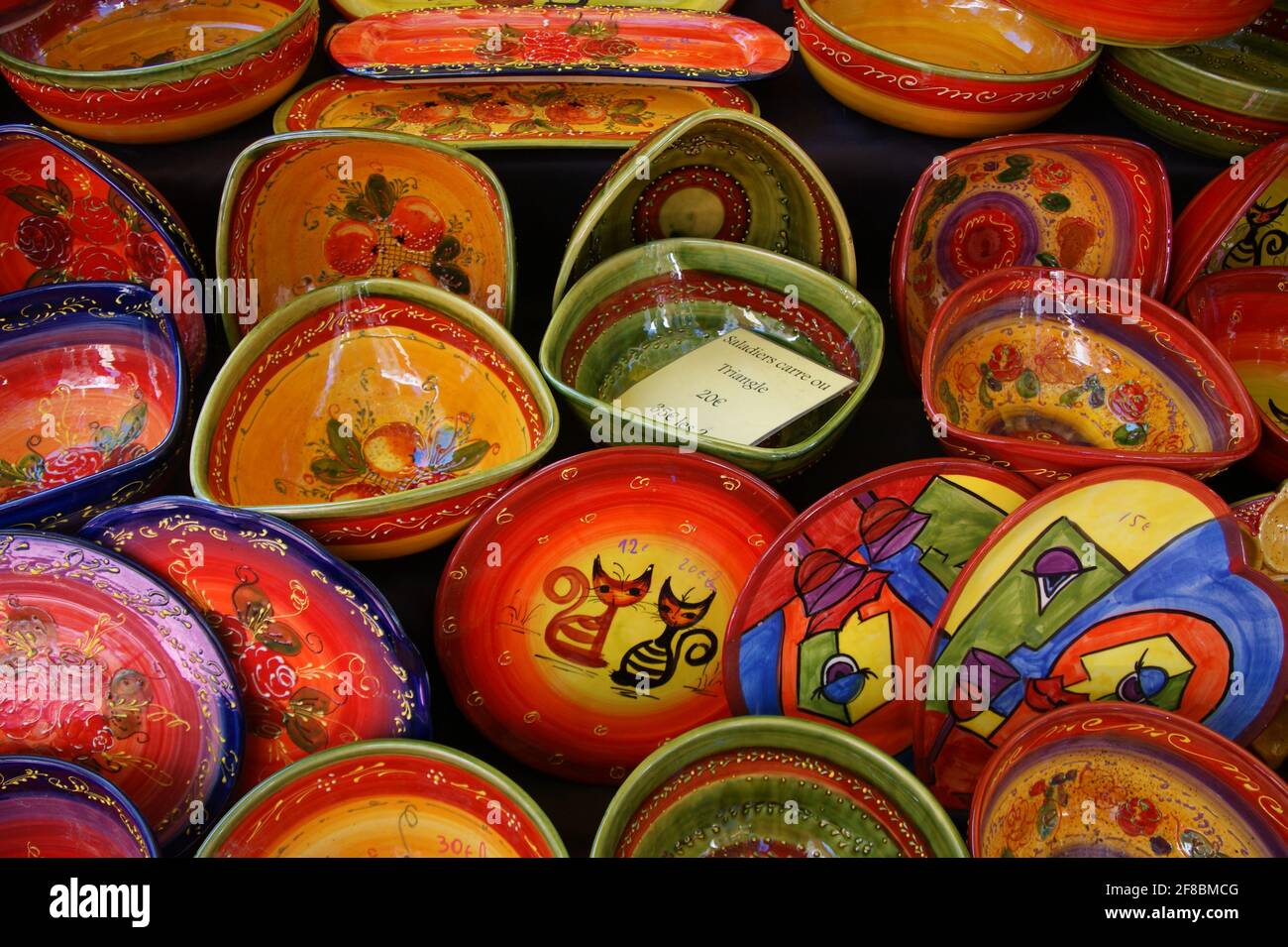 Assiettes à salade peintes à la main avec une sélection colorée de motifs à vendre sur un stand du marché français. Banque D'Images