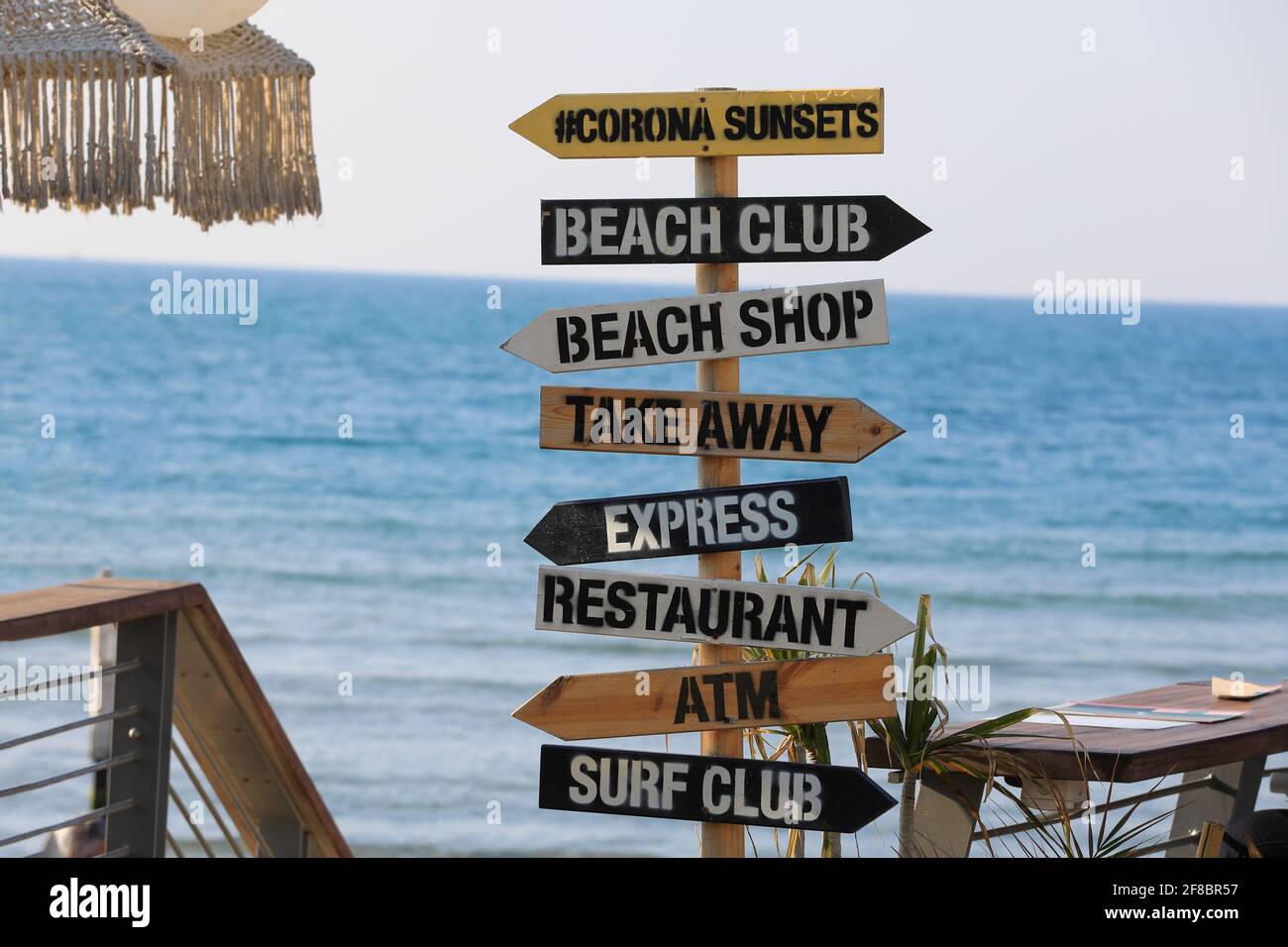 Panneau de direction sur fond de mer. Pointeur en bois vers la plage, club de surf, magasin, guichet automatique. Banque D'Images