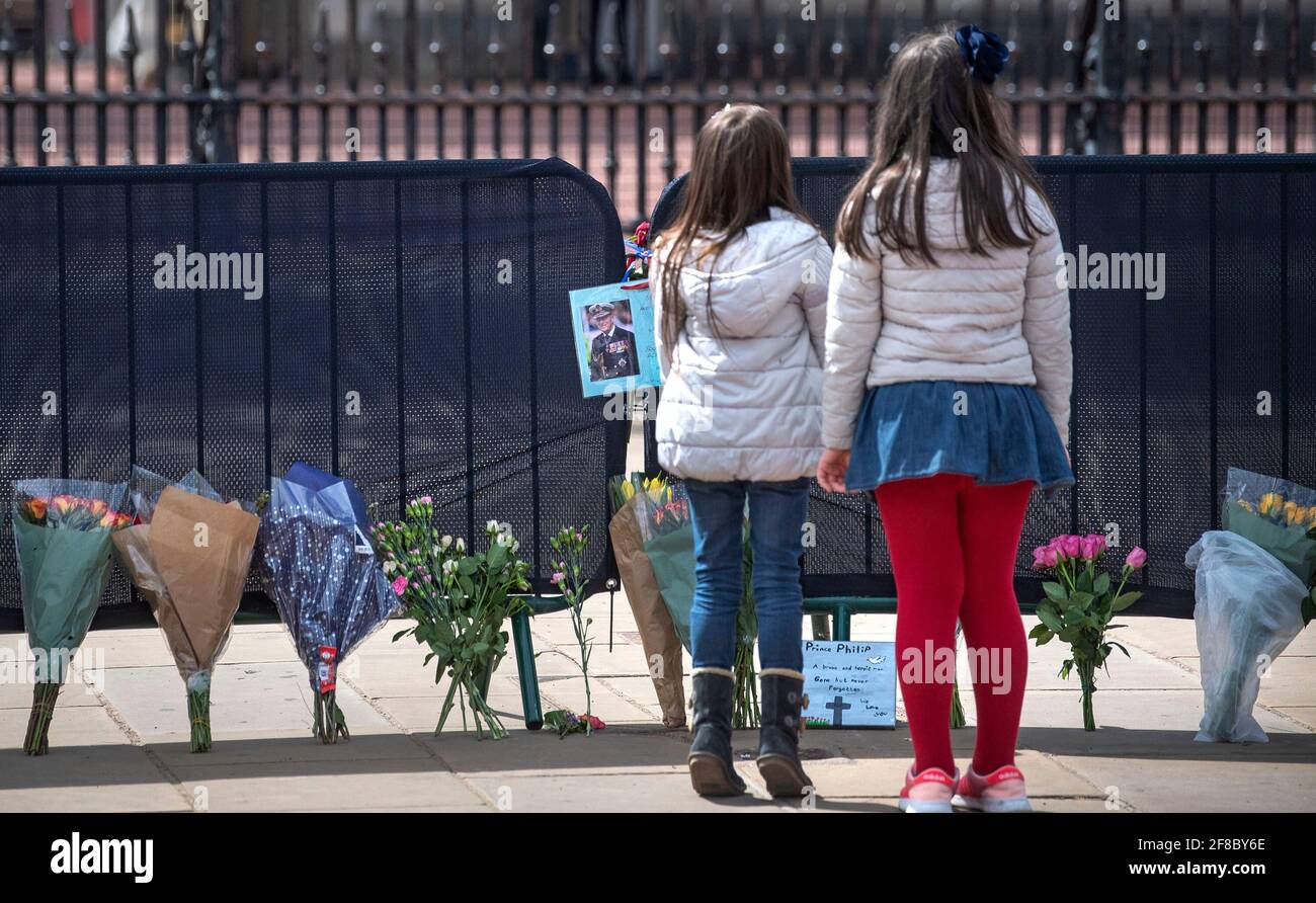 Deux filles regardent des fleurs et des messages laissés par le public à l'extérieur de Buckingham Palace, Londres, après la mort du duc d'Édimbourg, vendredi, à l'âge de 99 ans. Date de la photo: Mardi 13 avril 2021. Banque D'Images