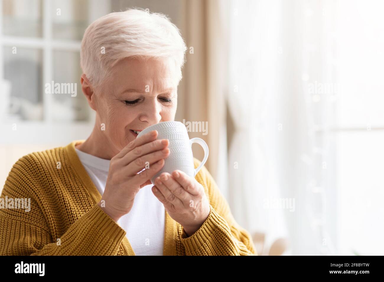 Gros plan sur une femme âgée qui boit du café ou du thé Banque D'Images