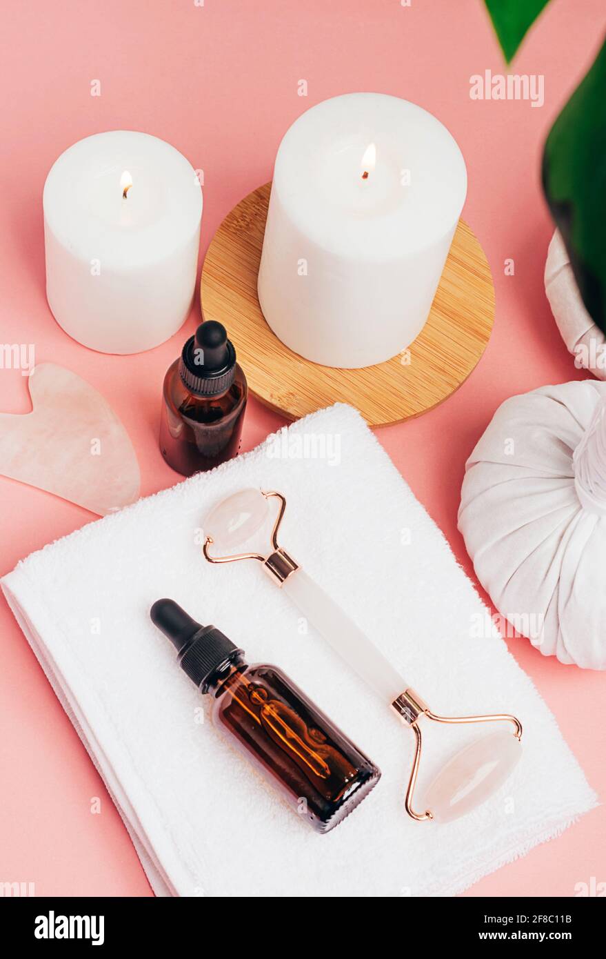 Composition spa sur fond rose pastel. Cosmétiques naturels bio bouteille d'huile, crème, argile, sel, outil de massage gua sha accessoires plan Banque D'Images