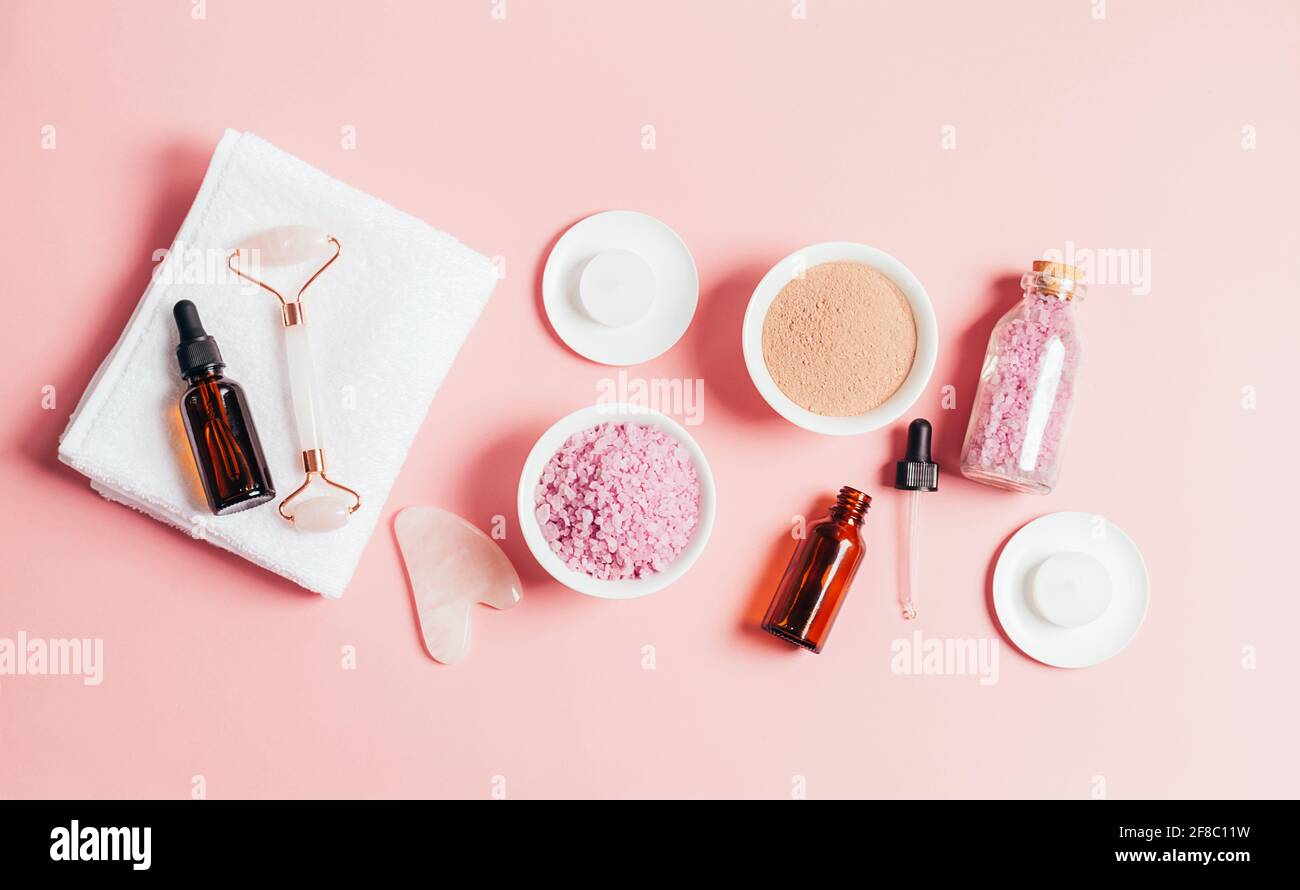 Composition spa sur fond rose pastel. Cosmétiques naturels bio bouteille d'huile, crème, argile, sel, outil de massage gua sha accessoires plan Banque D'Images