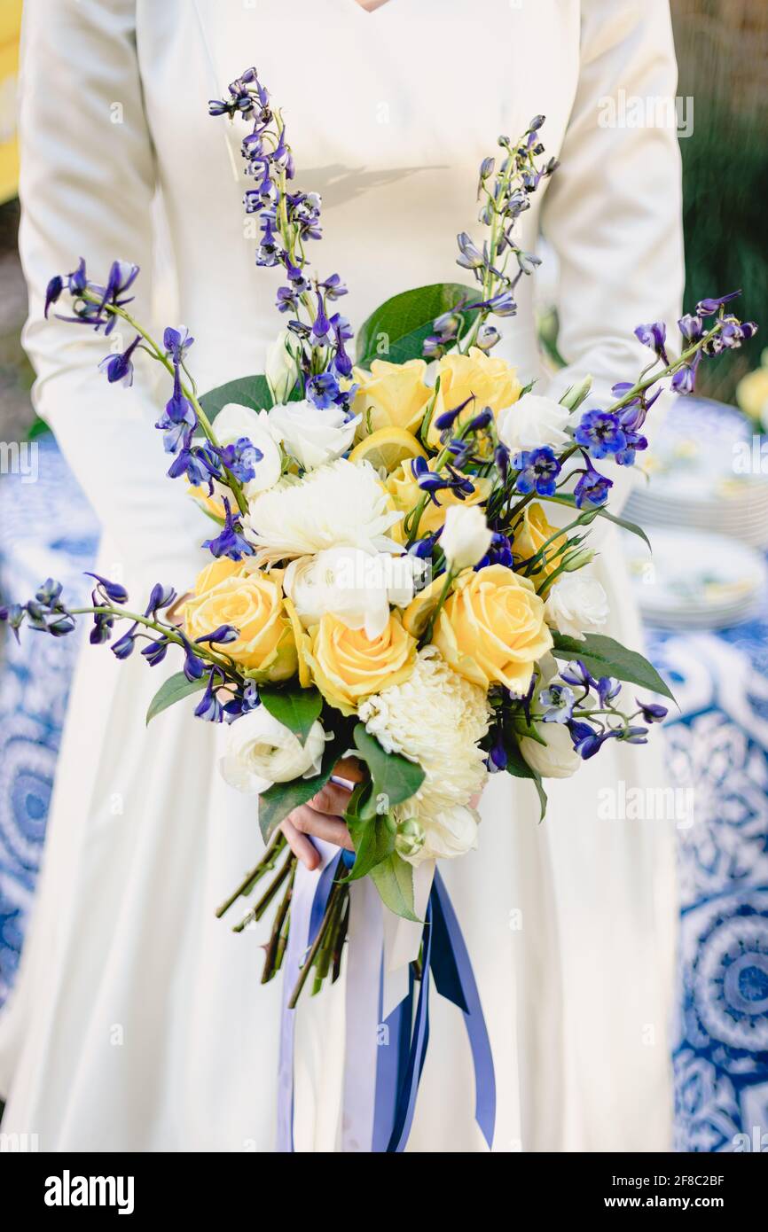 Mariée tient beau bouquet de mariage vibrant de jaune et blanc roses avec  touches bleu marine Photo Stock - Alamy