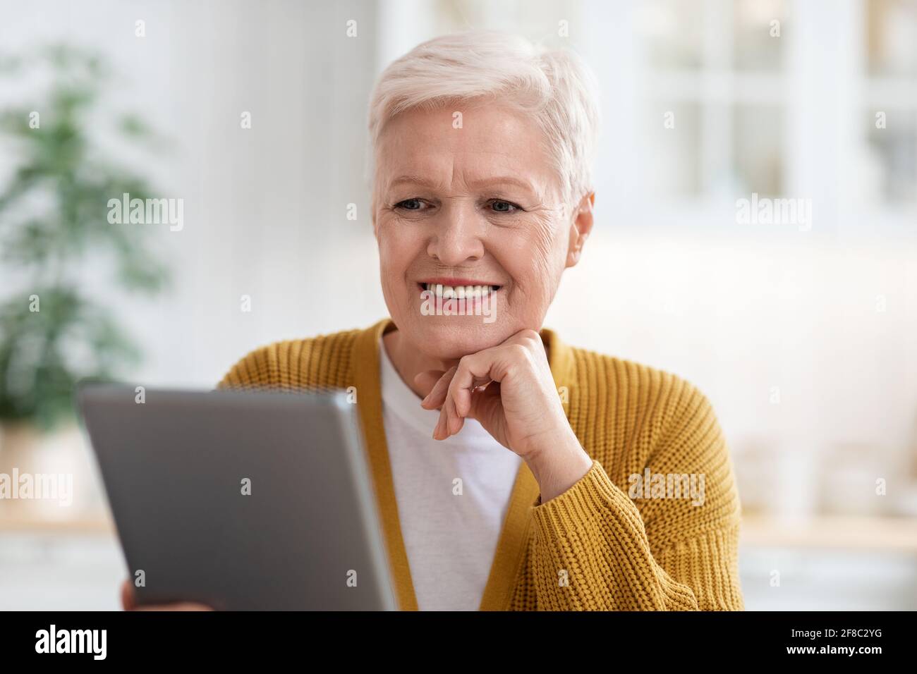 Bonne vieille femme utilisant une tablette numérique dans la cuisine, gros plan Banque D'Images