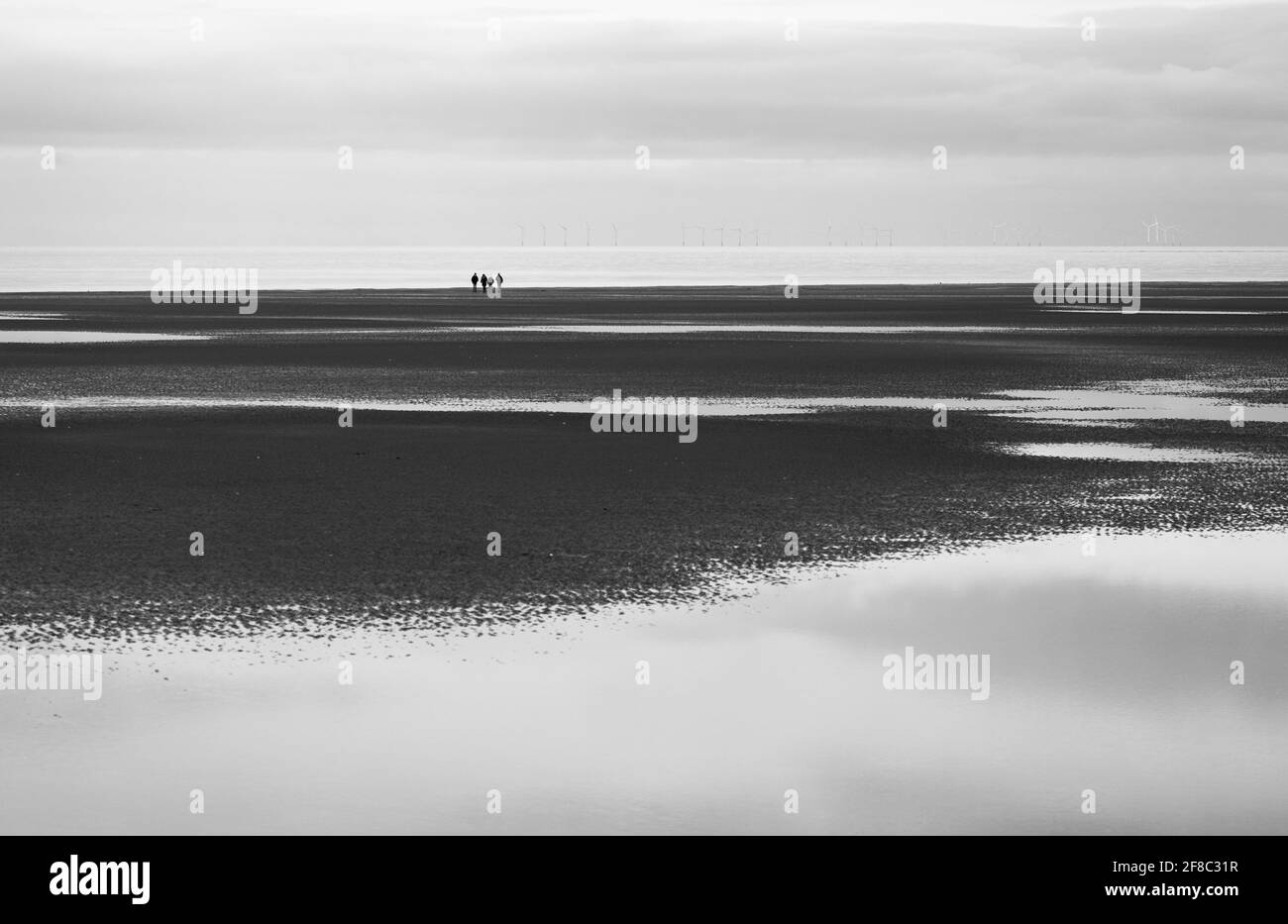 Groupe de quatre personnes au loin sur la plage à Holme-Next-the-Sea, Norfolk, Angleterre, Royaume-Uni. Banque D'Images