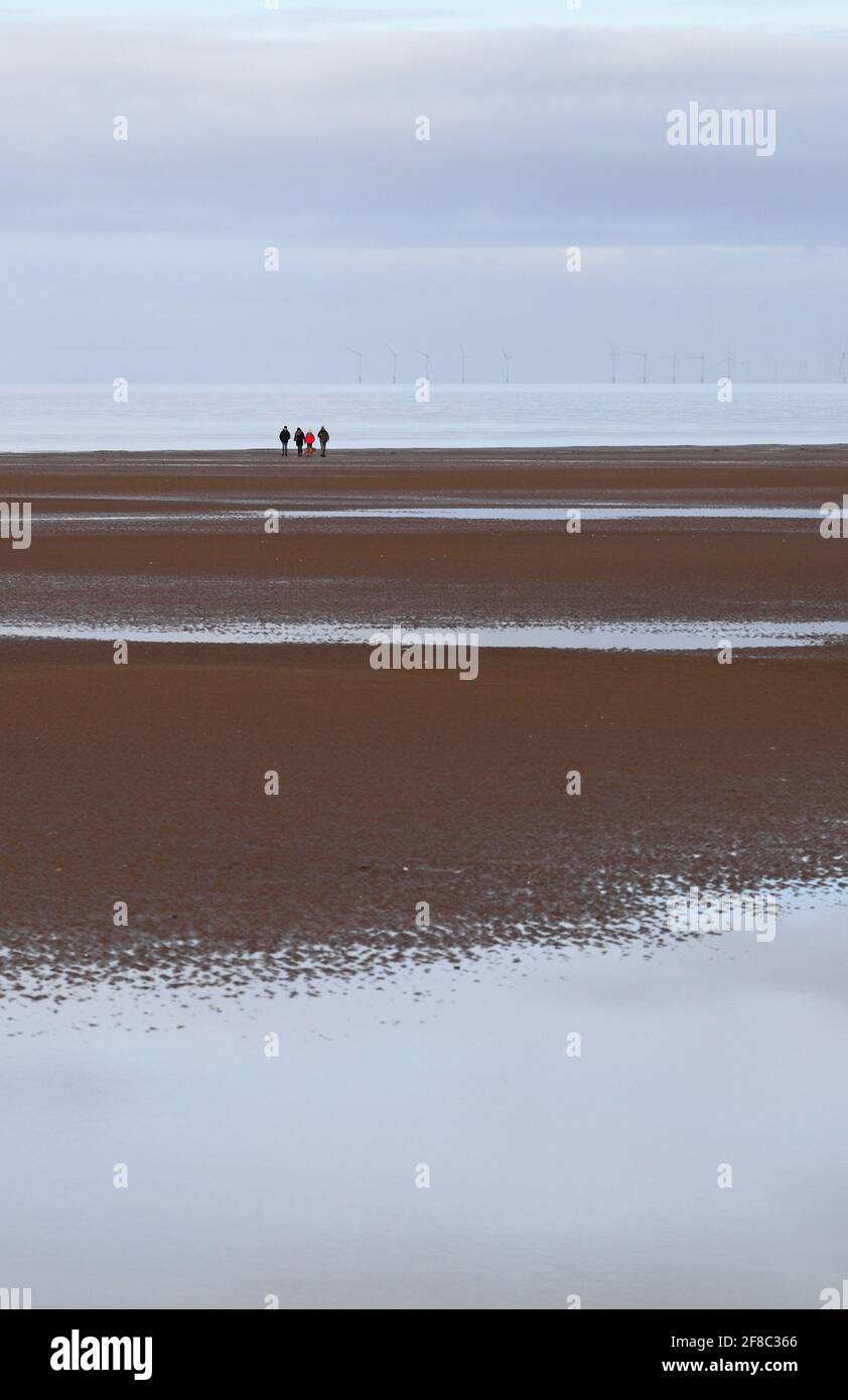 Groupe de quatre personnes au loin sur la plage à Holme-Next-the-Sea, Norfolk, Angleterre, Royaume-Uni. Banque D'Images