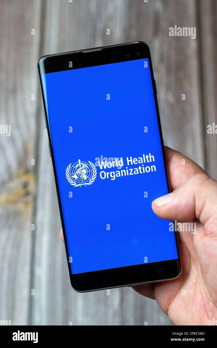 Un téléphone mobile ou mobile tenu dans un Main avec l'application de l'Organisation mondiale de la santé ouverte à l'écran Banque D'Images