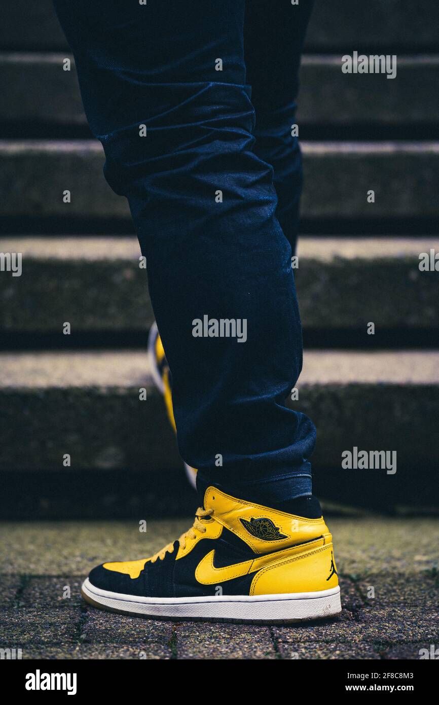 VANCOUVER, CANADA - 12 avril 2021 : angle de chaussure bas d'un homme en  jeans bleu foncé portant la sneaker Air Jordan 1s RETRO New Love debout sur  le sol en ciment