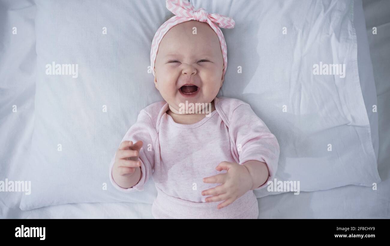 Vue De Dessus De Bebe Fille Bouleversee Dans Le Bandeau Avec Noeud Pleurer En Etant Allonge Sur Le Lit Photo Stock Alamy