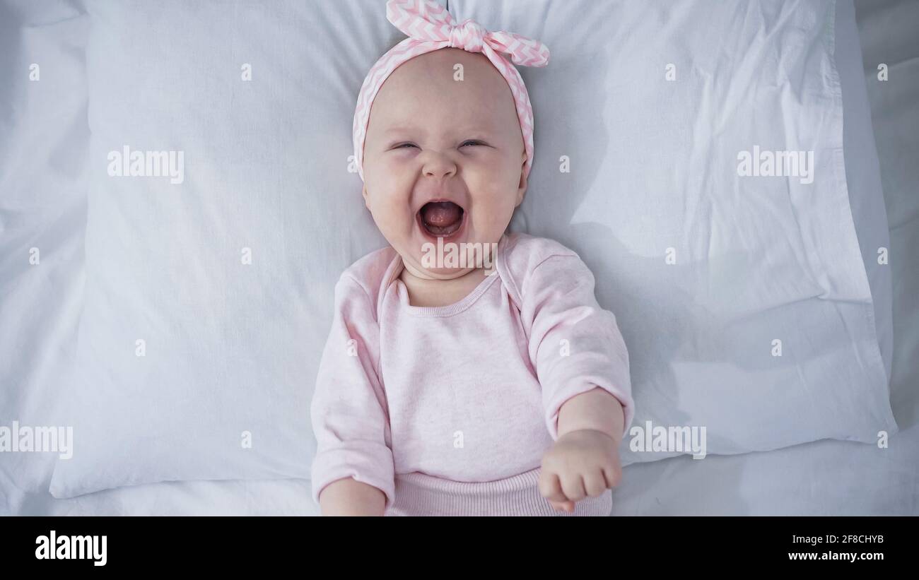 Vue De Dessus De Bebe Fille Dans Le Bandeau Avec Des Pleurs D Arc En Etant Allonge Sur Le Lit Photo Stock Alamy