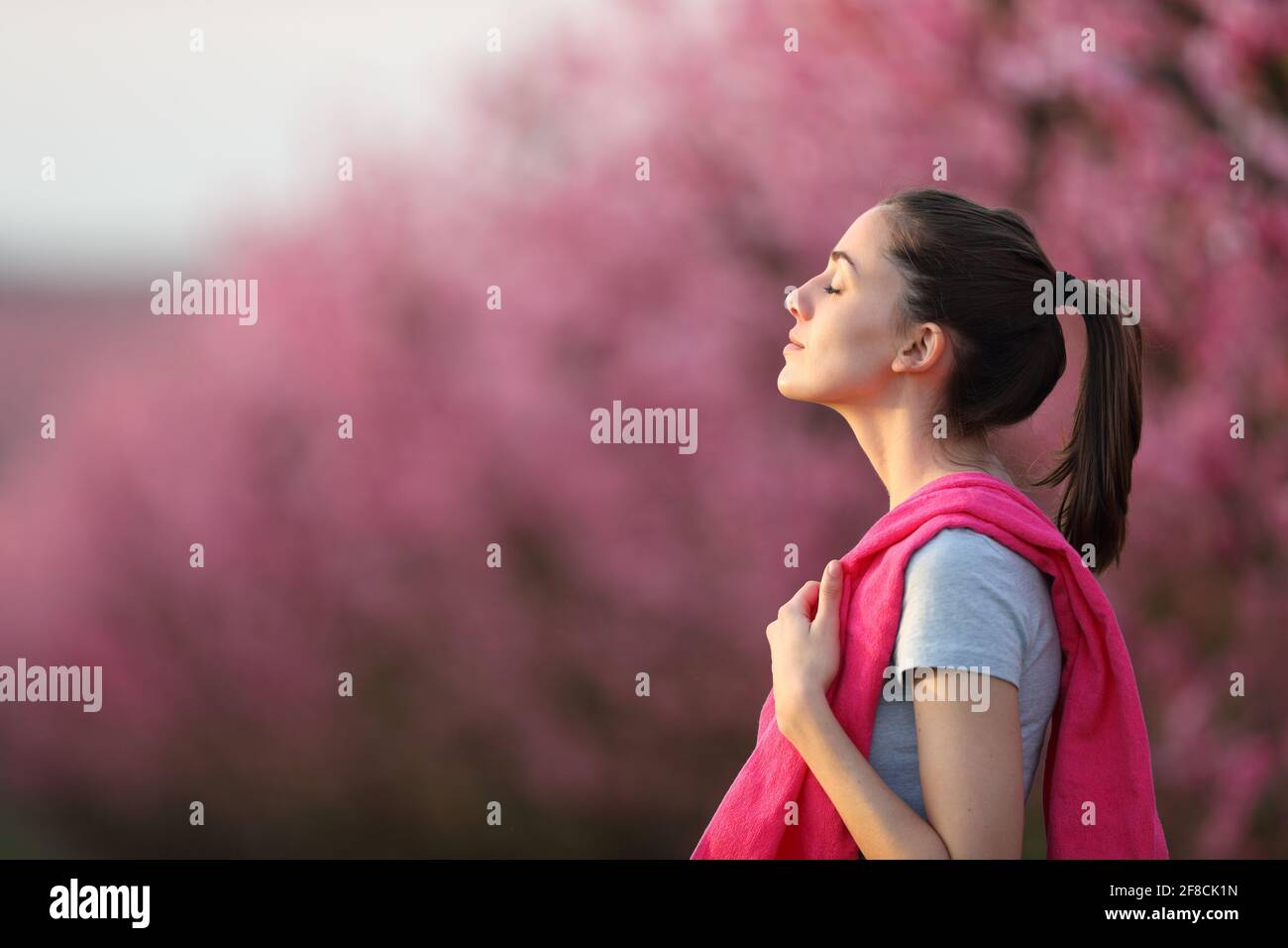Profil d'une sportswoman respirant de l'air frais après le sport un champ à fleurs roses Banque D'Images