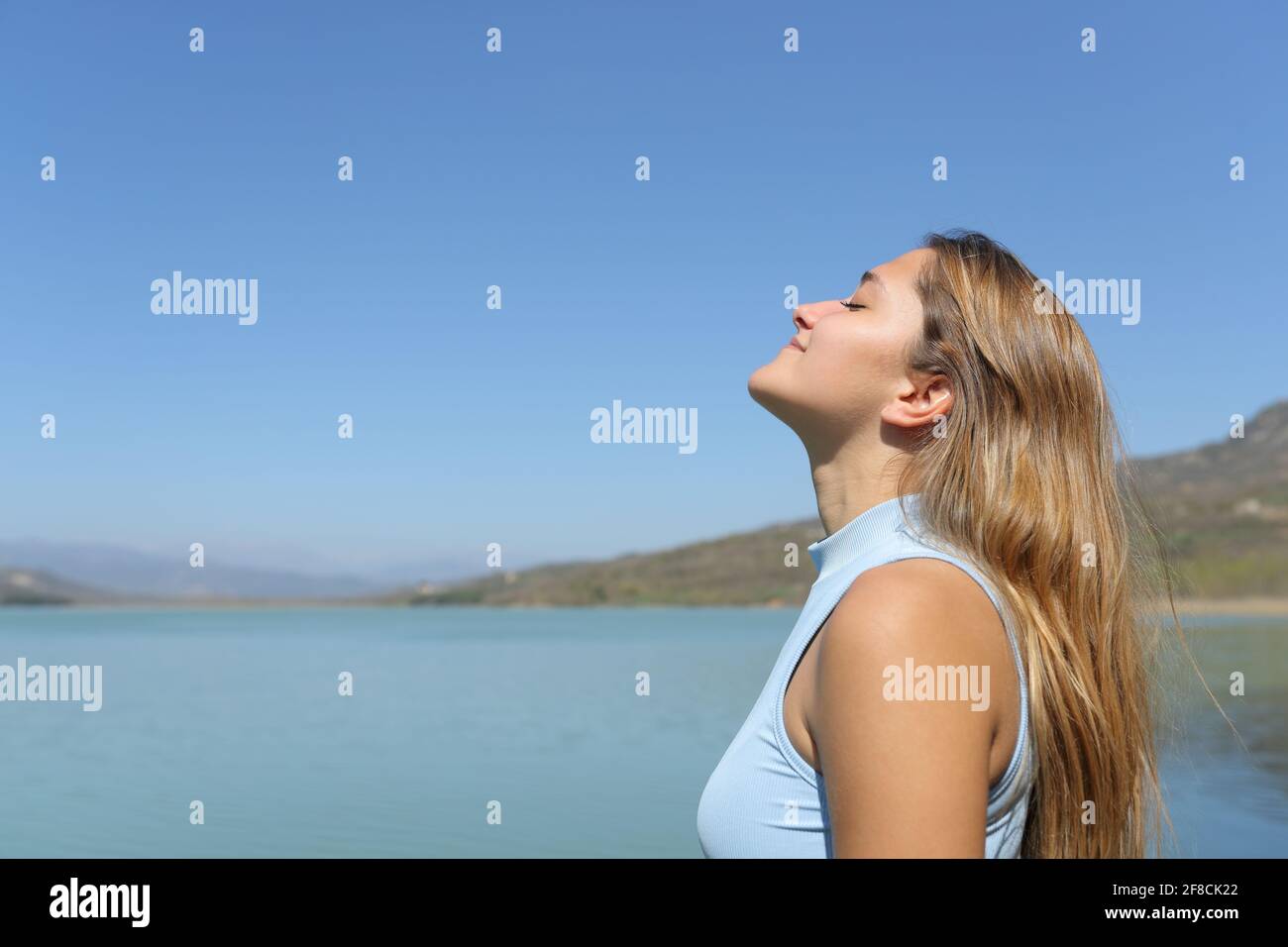 Vue latérale d'une femme détendue respirant de l'air frais dans un lac Banque D'Images