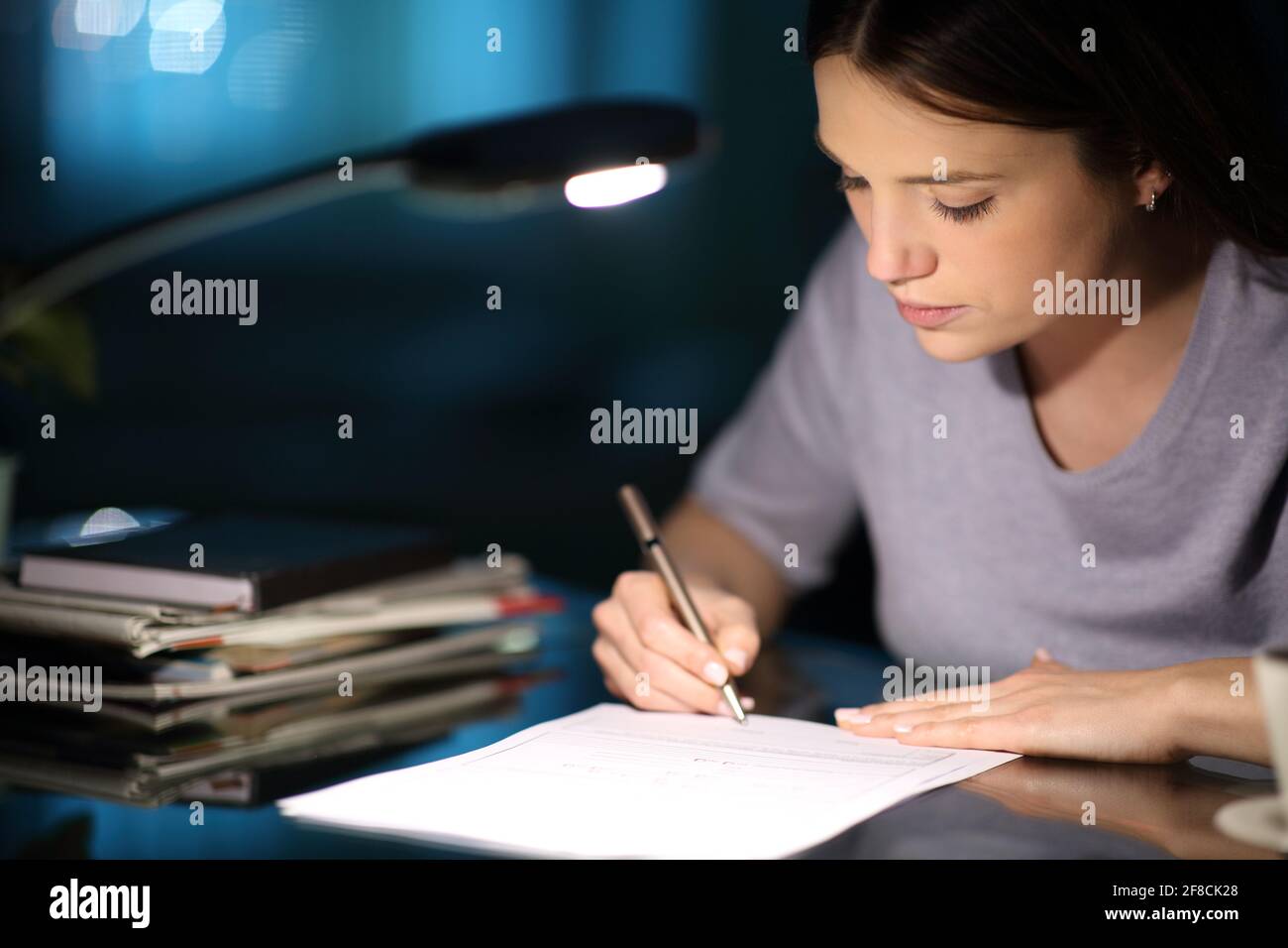 Femme sérieuse signant la forme dans la nuit à la maison Banque D'Images