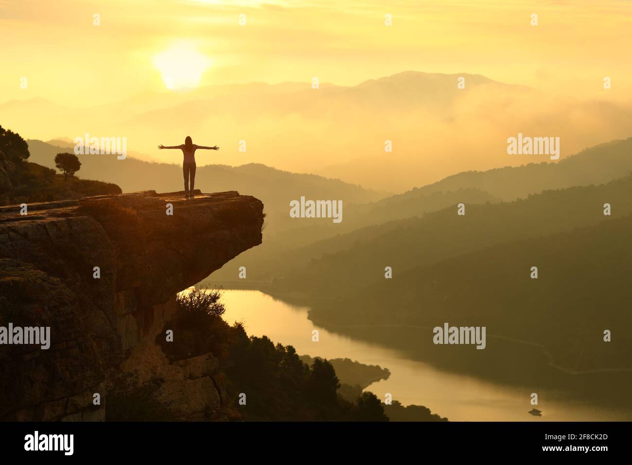 Vue arrière portrait d'une silhouette de femme célébrant le succès dans un magnifique paysage de coucher de soleil Banque D'Images