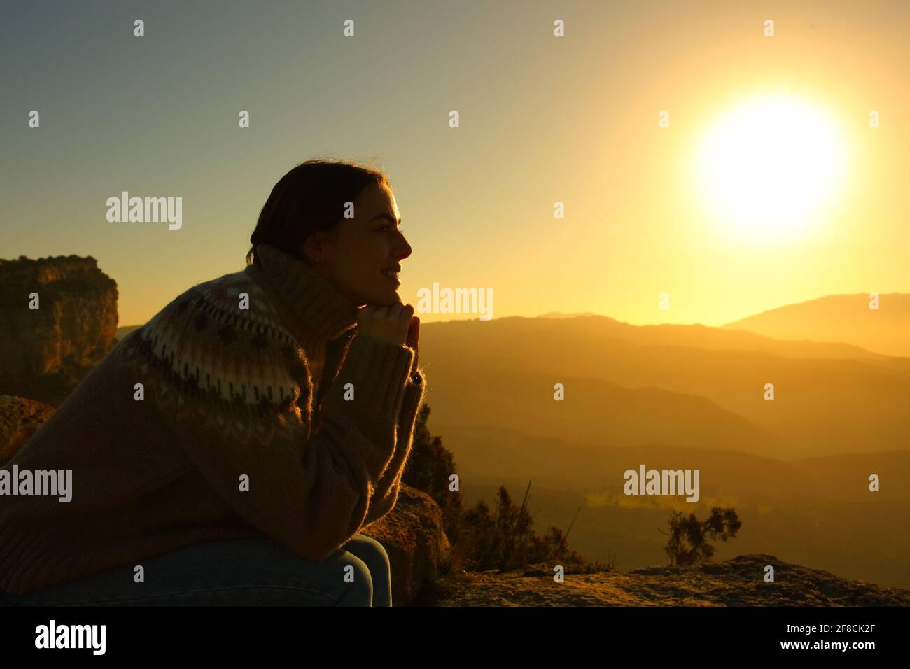 Profil de contre-jour d'une silhouette de femme méditant au coucher du soleil à l'intérieur la montagne Banque D'Images