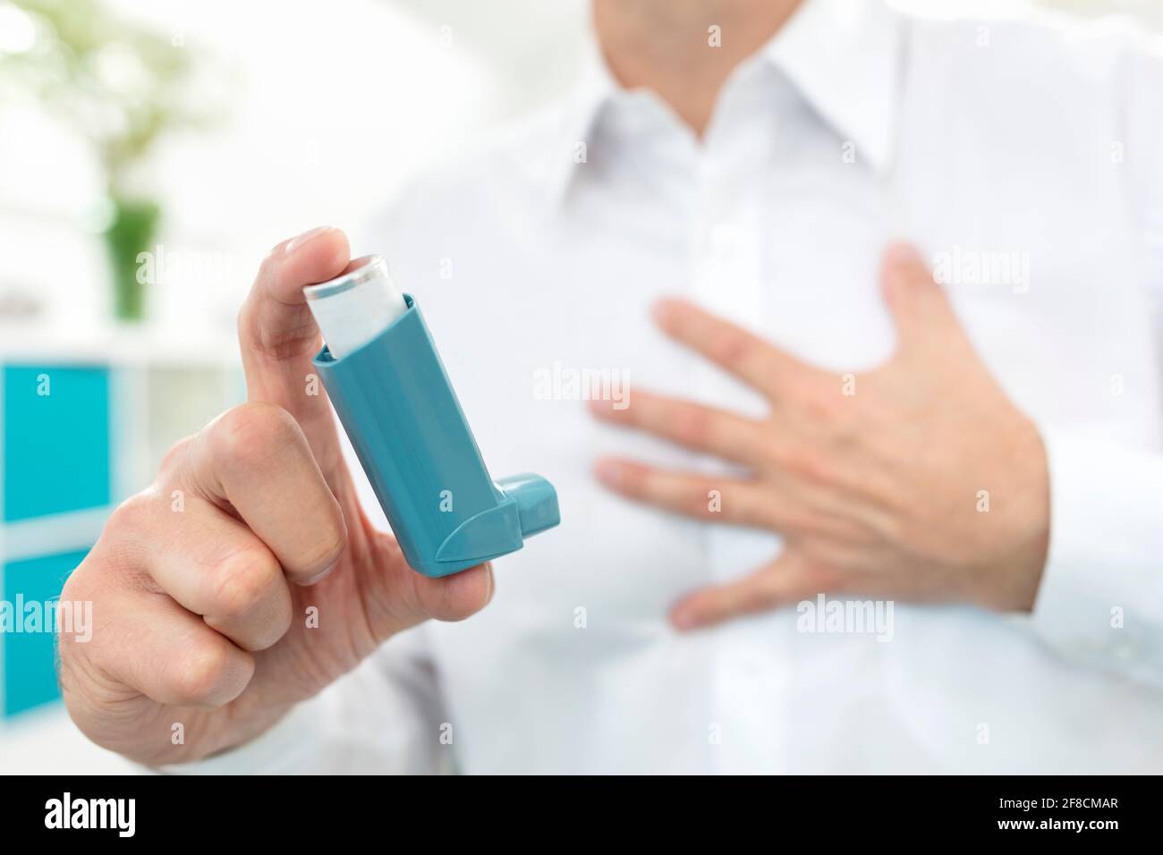 Homme utilisant des médicaments d'inhalateur d'asthme bleu avec des difficultés respiratoires Banque D'Images