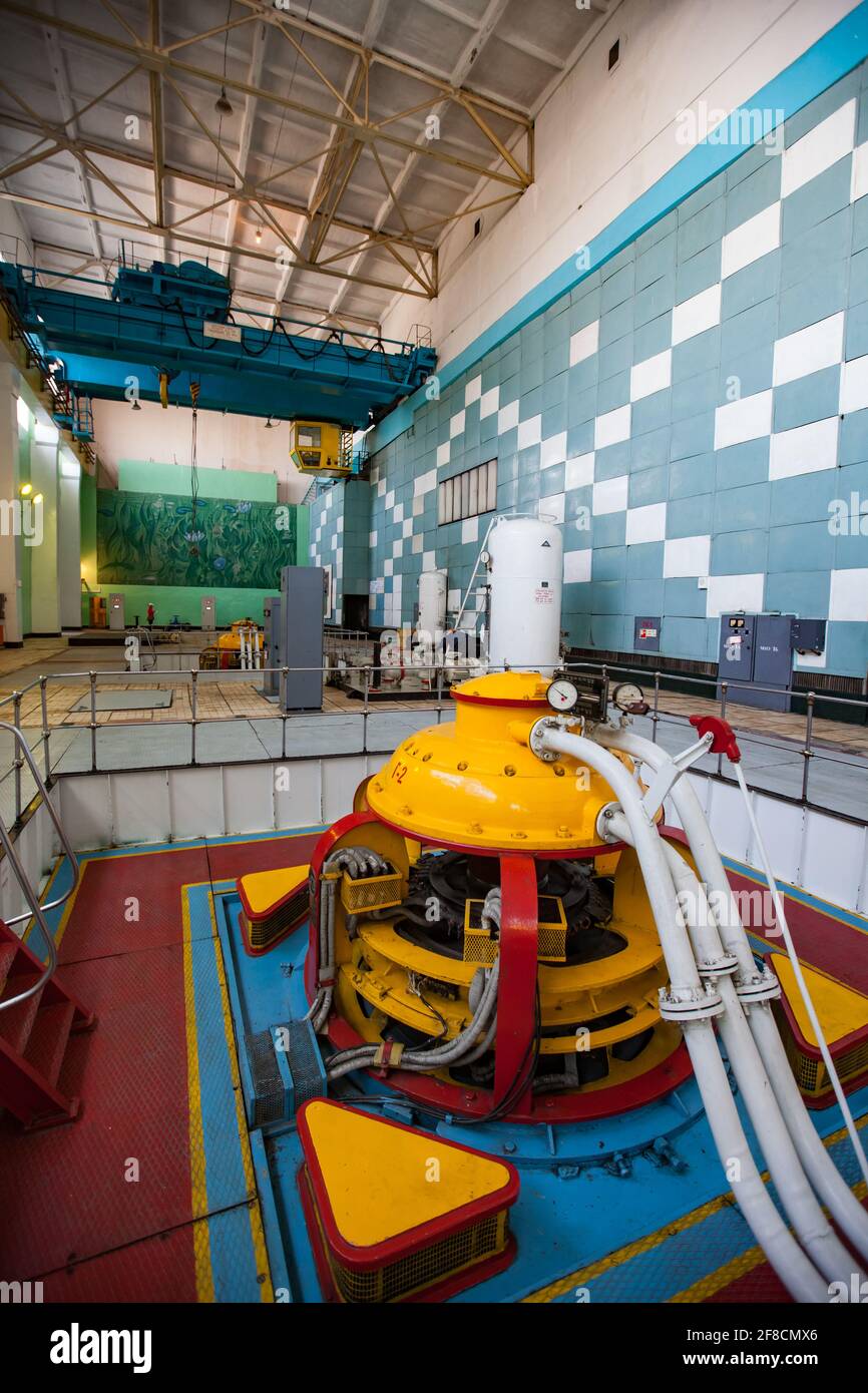 Salle des machines de la centrale hydroélectrique de Shardara. Générateur jaune et pont roulant bleu. Intérieur soviétique d'époque. Kazakhstan. Banque D'Images