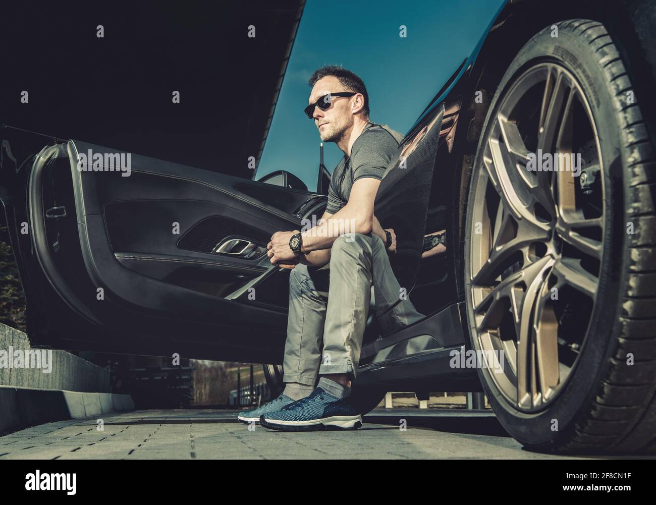 Chauffeur caucasien dans ses 40 sièges à l'intérieur de sa Sporty car exotique moderne et appréciant le temps chaud d'été. Thème de l'itinéraire. Banque D'Images