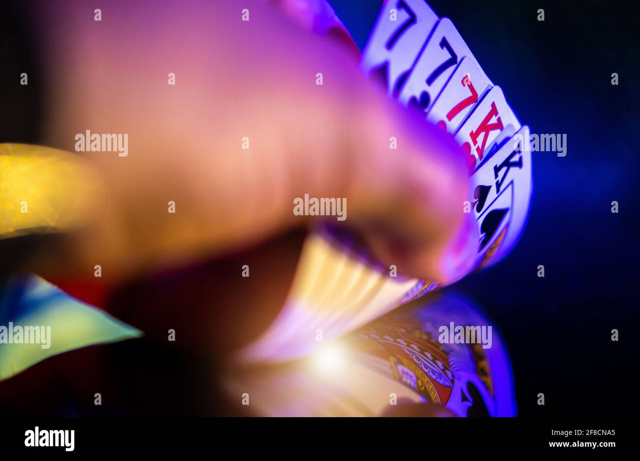 Joueur de poker regardant ses cartes. Une maison complète entre les mains du joueur gros plan. Table sombre vitreux avec réflexions. Jeux de casino et divertissement T Banque D'Images