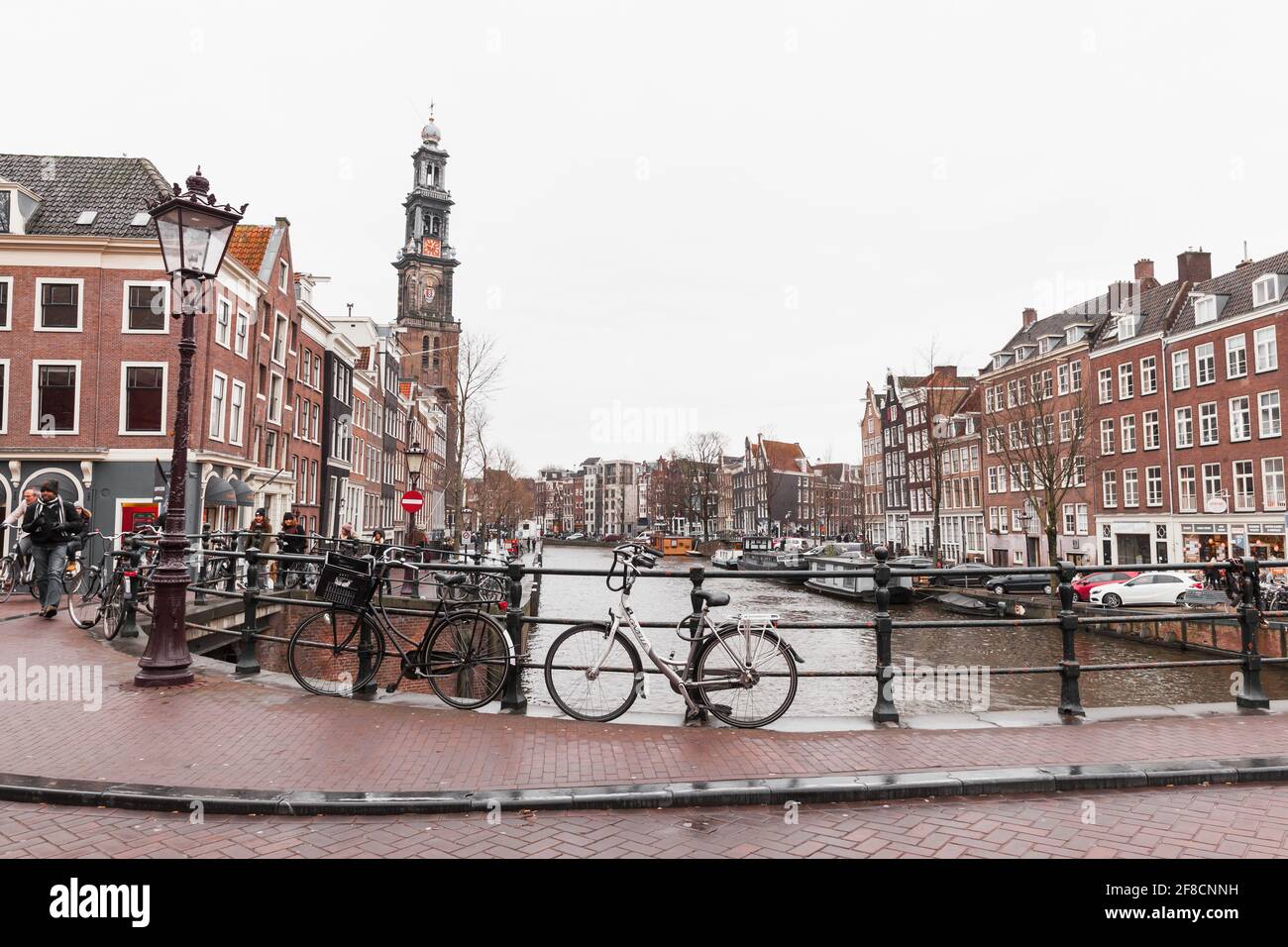 Amsterdam, pays-Bas - 24 février 2017 : stand de vélos garés sur le pont dans la vieille ville d'Amsterdam, les gens ordinaires marchent à proximité Banque D'Images