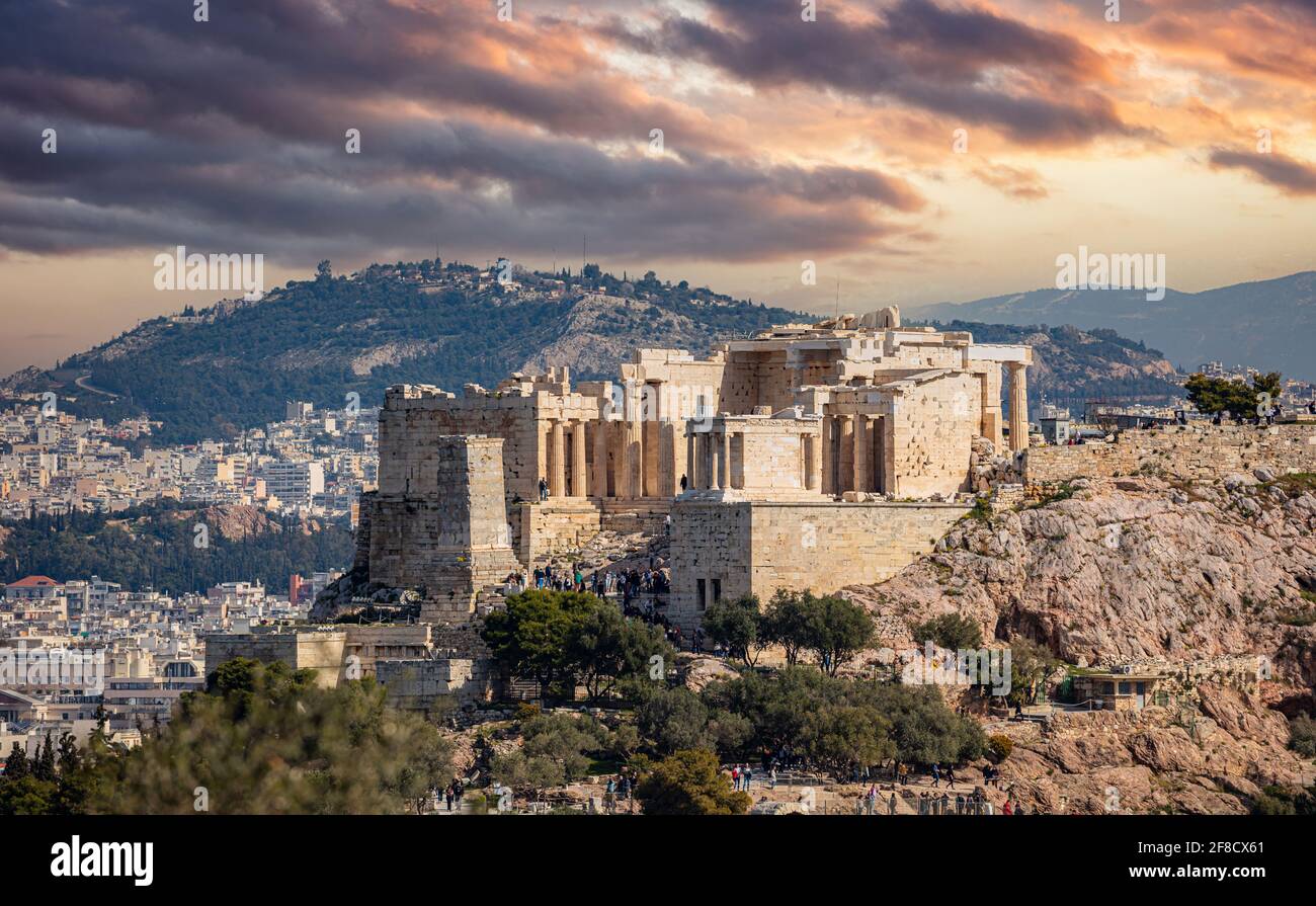 Athènes, Grèce. Porte Acropolis propylaea et monument Agrippa vue depuis la colline de Philopapos. Ciel nuageux et coloré au soleil Banque D'Images