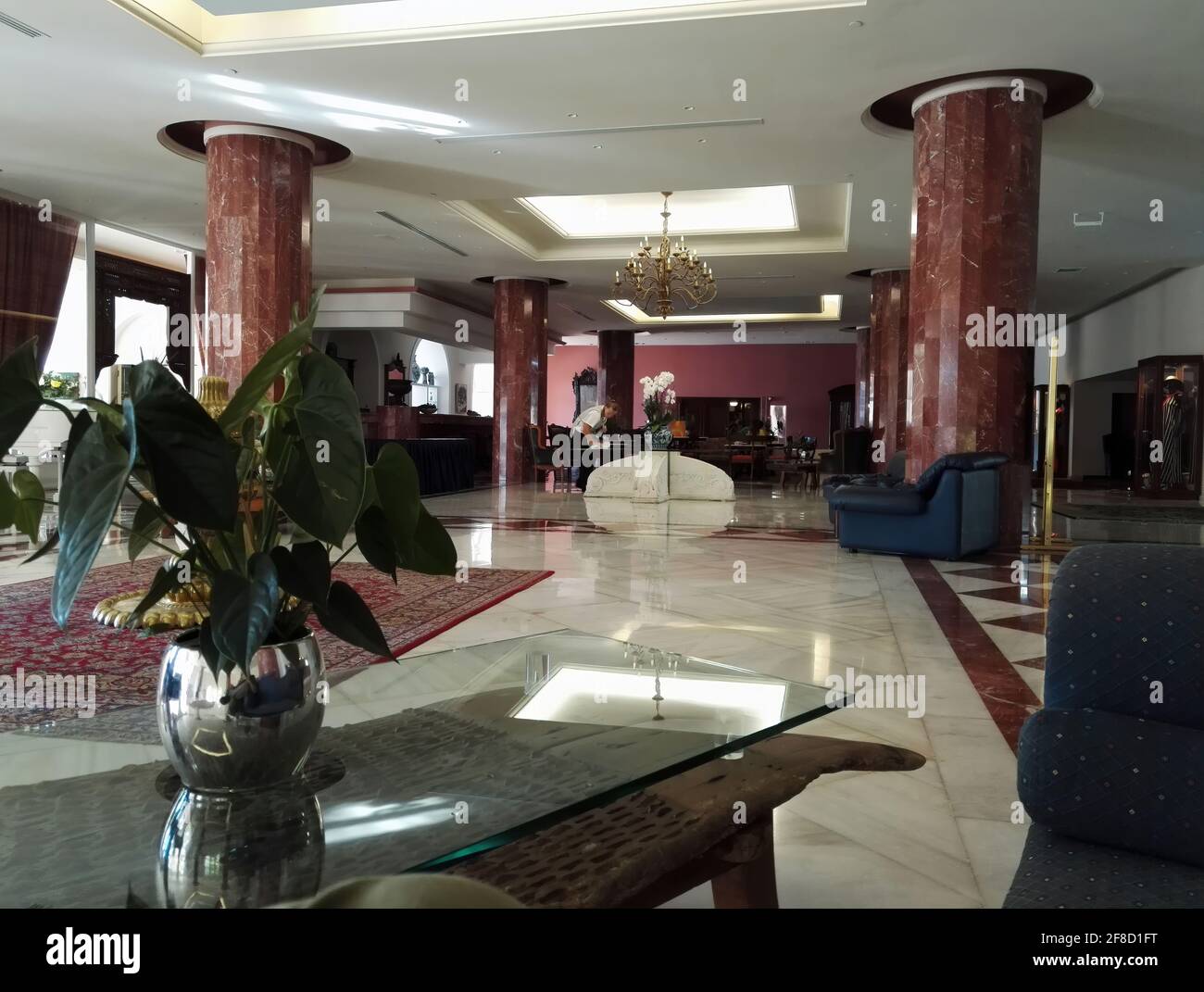 Kreta, Grèce - 08 octobre 2017 : intérieur d'un hôtel nettoyé au hasard avec piliers, plante sur vase, lustre et une personne non identifiée qui nettoie le t Banque D'Images