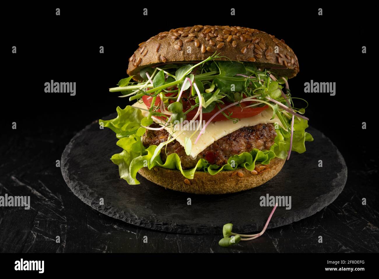 sandwich fermé dans un petit pain avec concombre, tomate et microverts. Hamburger maison Banque D'Images