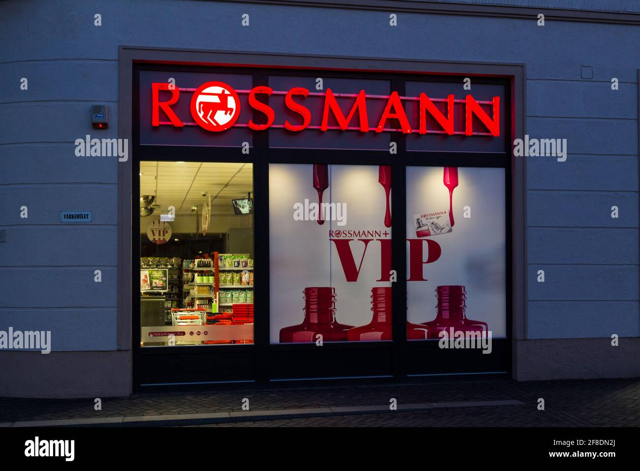 Boutique devant le dadstore Rossmann illuminé dans la soirée, Sopron, Hongrie Banque D'Images