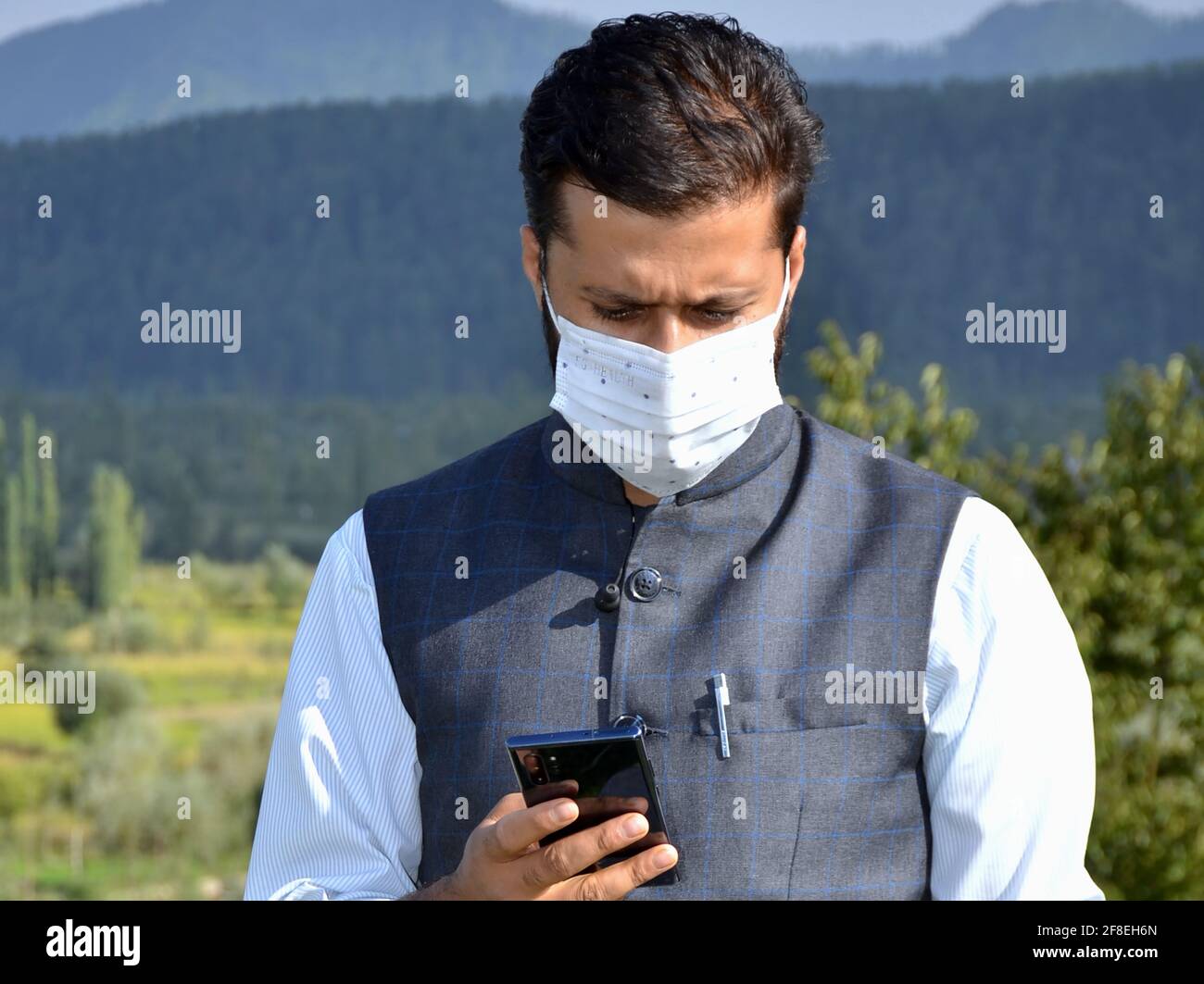 Asian Man portant le masque parle au téléphone à un endroit magnifique après le verrouillage du coronavirus. Banque D'Images