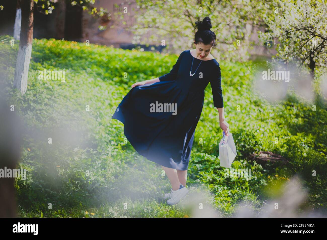 Bonne femme marchant dans le jardin de cerisier de printemps Banque D'Images