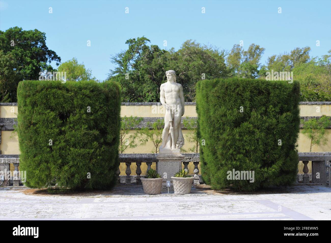Vue extérieure sur le musée et le jardin de Vizcaya. Paysage de la nature avec une sculpture de statue classique entre deux grandes haies de coupe carrée. Banque D'Images Vue extérieure sur le musée et le jardin de Vizcaya. Paysage de la nature avec une sculpture de statue classique entre deux grandes haies de coupe carrée. Banque D'Images