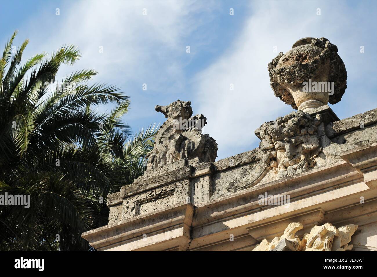 Statue en pierre suspendue, arche de dessins de la Renaissance italienne avec palmiers en arrière-plan. Banque D'Images