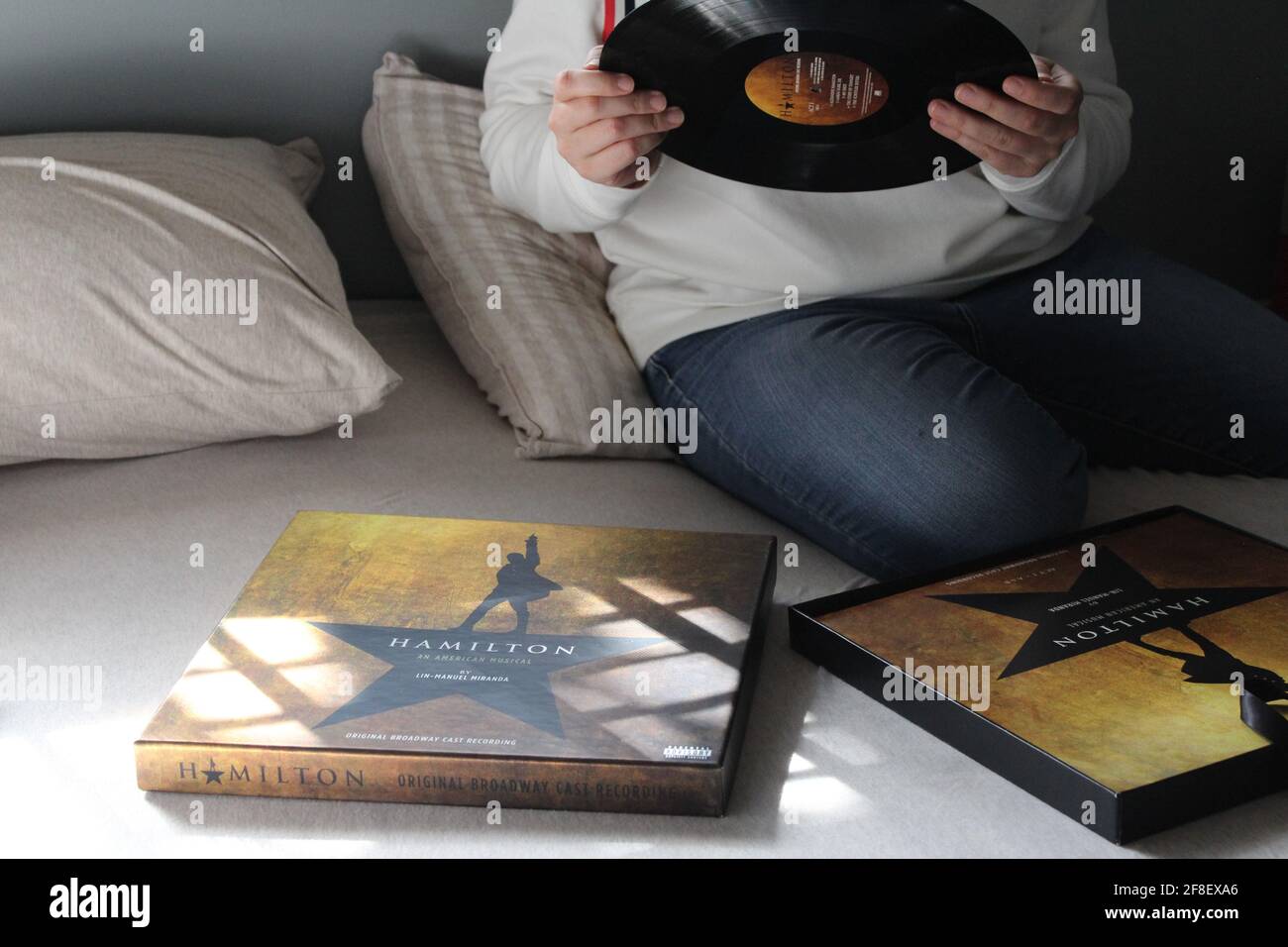 Femme à la recherche et à l'écoute du disque LP original Broadway Cast Recording Vinyl Record de Hamilton dans sa chambre. Banque D'Images