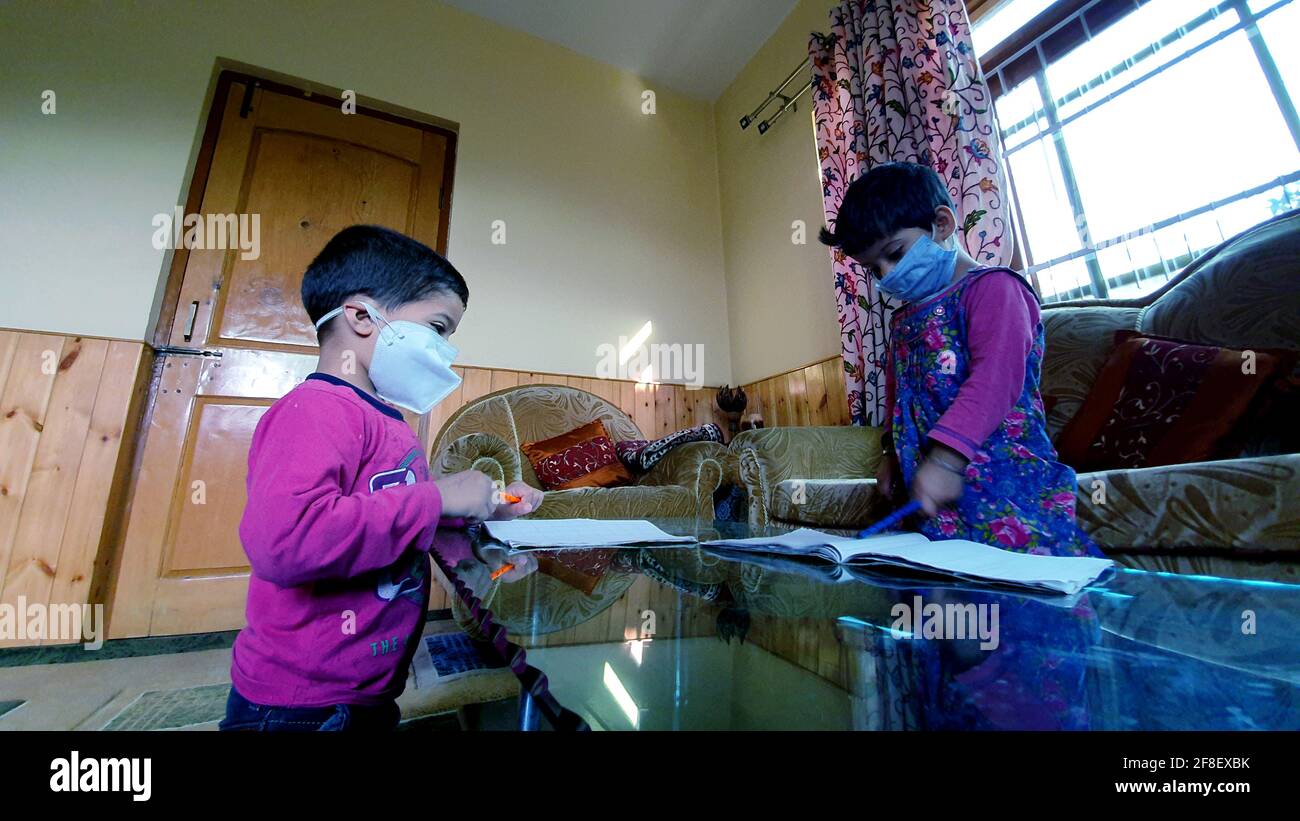 Des élèves masqués lisant et écrivant leur travail scolaire à la maison pendant le coronavirus pandémique. Les cours en ligne sont courants en raison de Covid 19. Banque D'Images