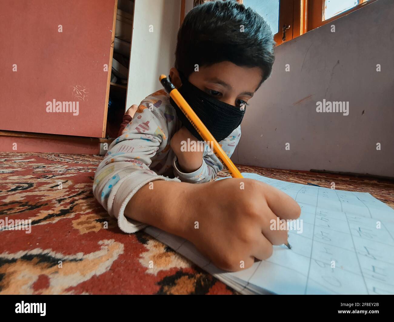 Les élèves portant des masques pour lire et écrire leur travail scolaire à la maison pendant le coronavirus pandémique. Les cours en ligne sont courants en raison de Covid 19. Banque D'Images