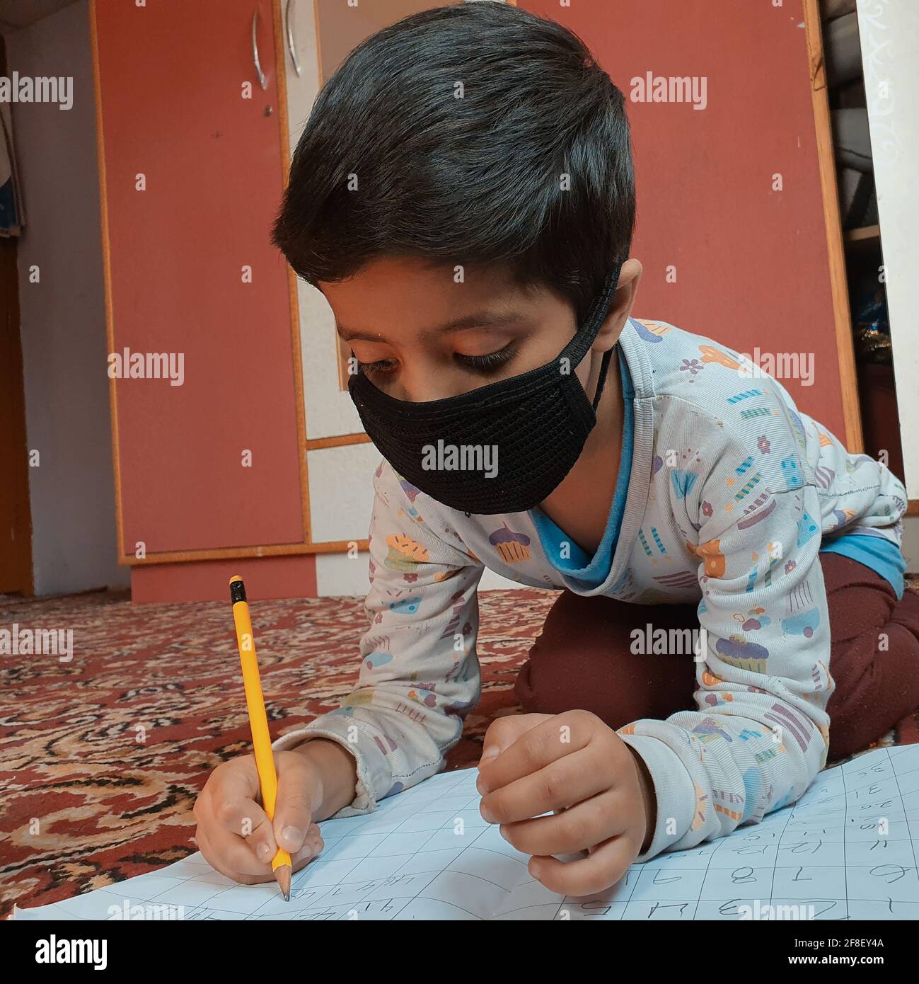 Les élèves portant des masques pour lire et écrire leur travail scolaire à la maison pendant le coronavirus pandémique. Les cours en ligne sont courants en raison de Covid 19. Banque D'Images