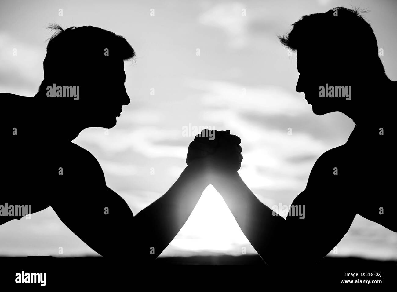 Deux hommes luttant. Comparaison rivalité, vs, défi, force. Coucher de soleil, lever du soleil. Banque D'Images
