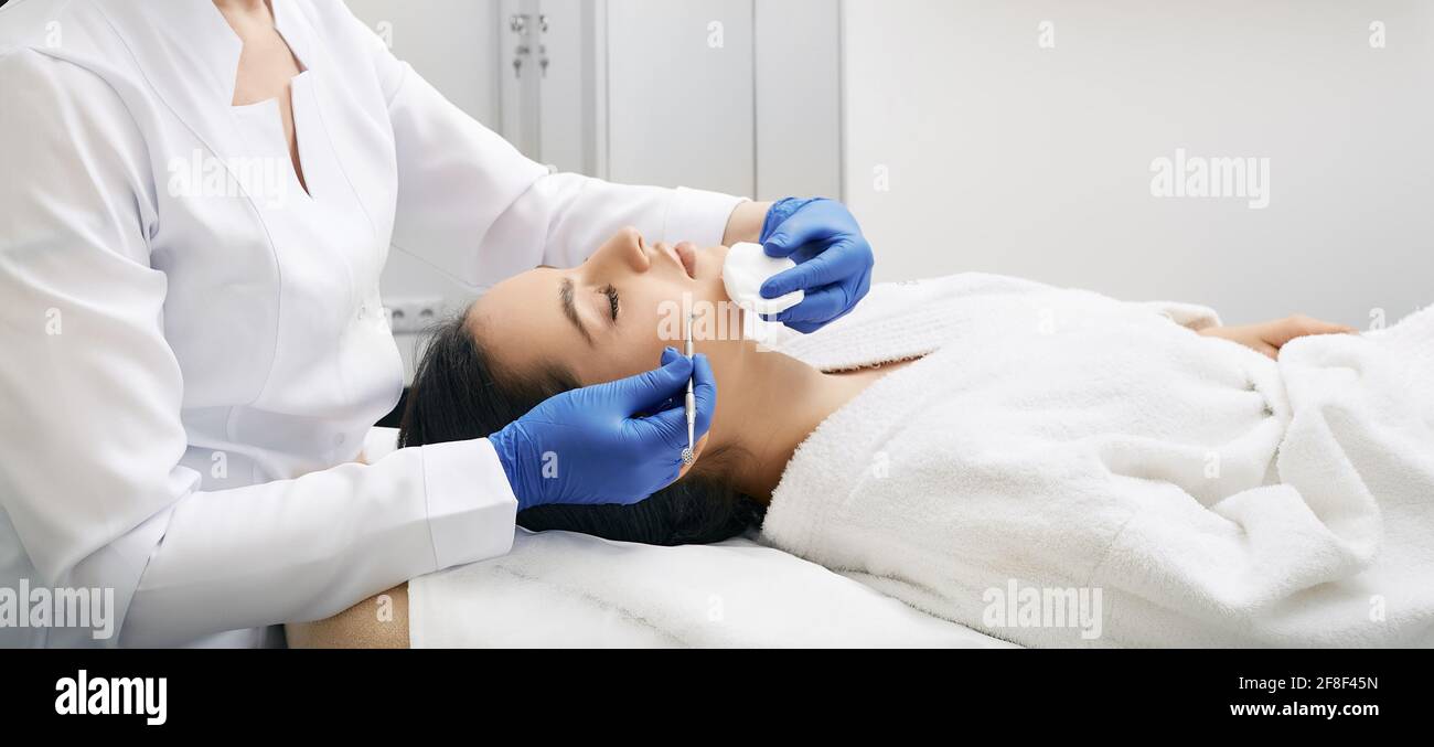 Brunette femme obtient nettoyage mécanique de la peau du visage des défauts et retrait de la tête noire dans une clinique médicale Banque D'Images