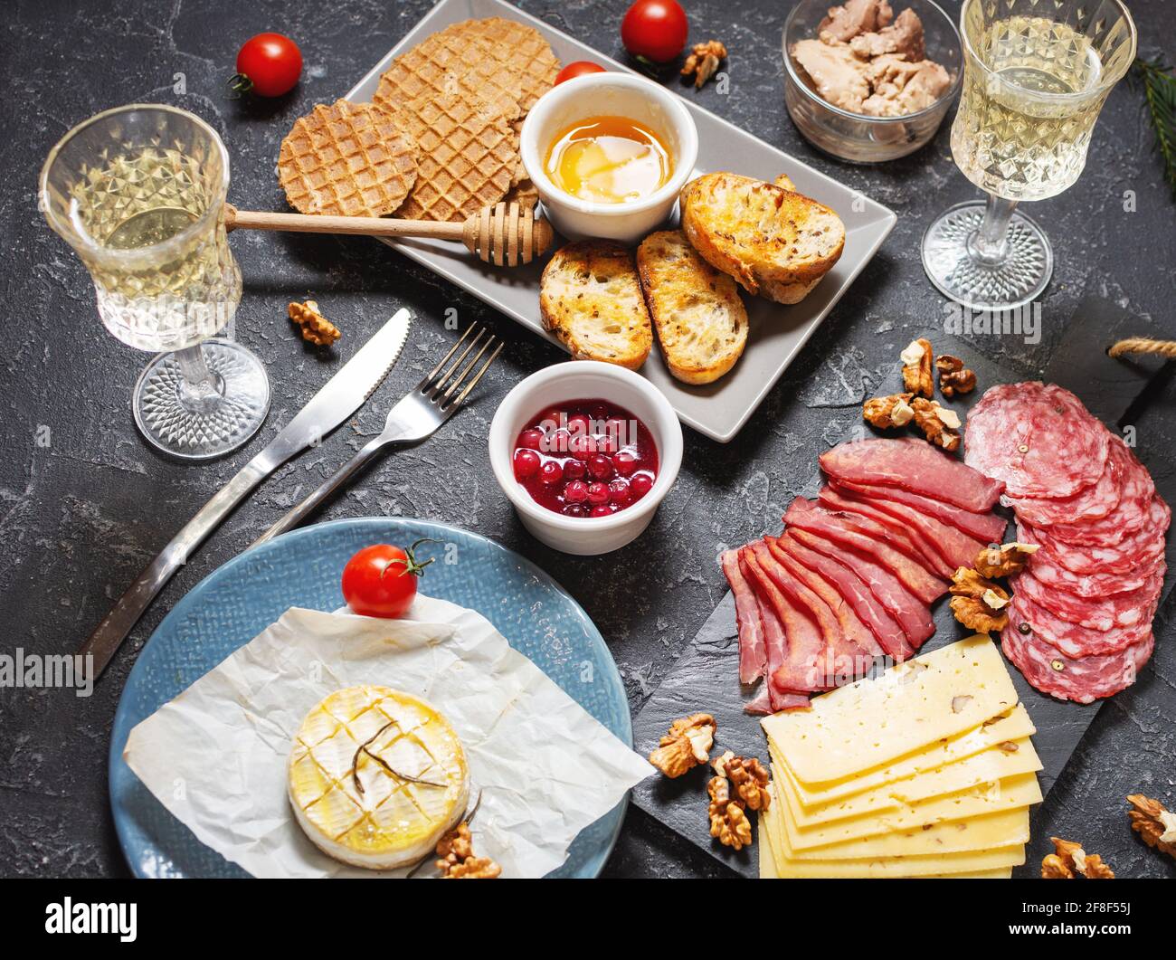 Assiette d'antipasti de viande froide avec pain, salami, tranches de jambon et fromage sur fond de pierre noire. Banque D'Images
