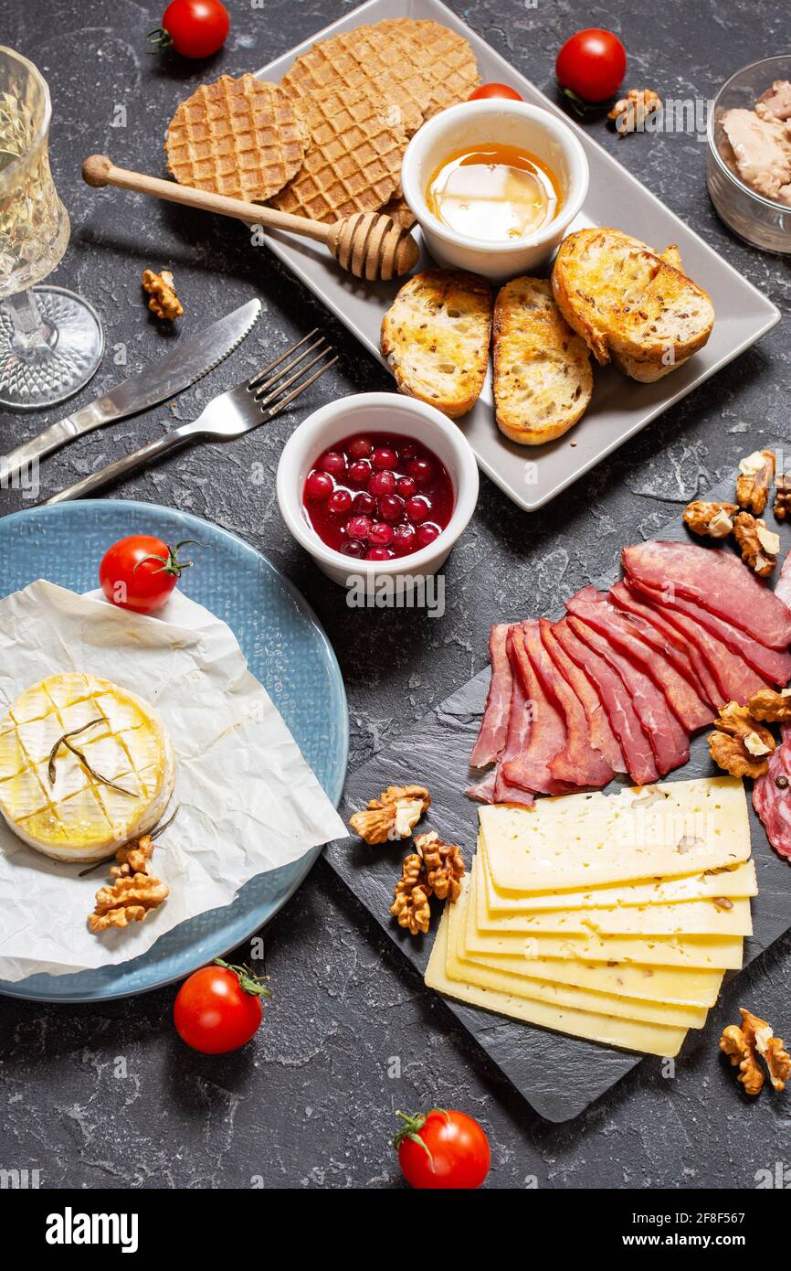Assiette d'antipasti de viande froide avec pain, salami, tranches de jambon et fromage sur fond de pierre noire. Banque D'Images