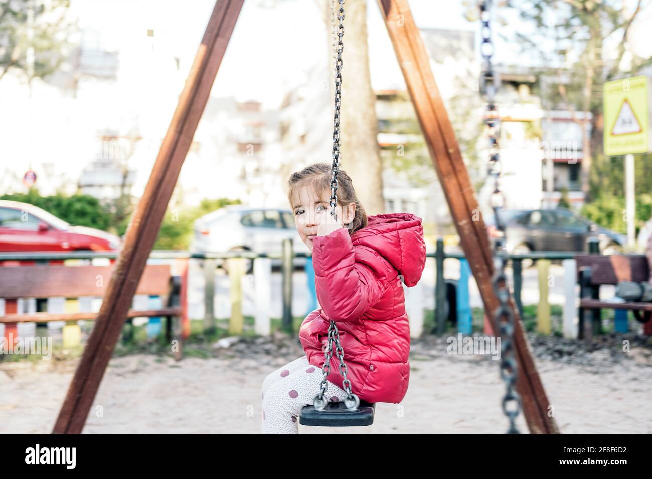 Une jeune fille en âge d'aller à l'école souriant joyeusement pendant que vous roulez sur le balançoires dans le parc Banque D'Images