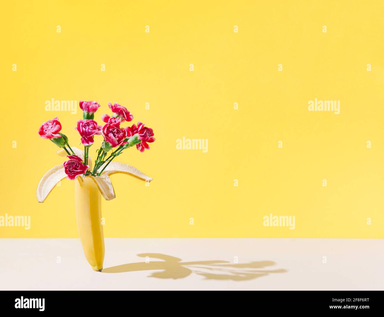 Aménagement créatif avec bouquet de fleurs naturelles et de fruits à la banane sur fond de sable pastel. Thème cadeau femme. Banque D'Images