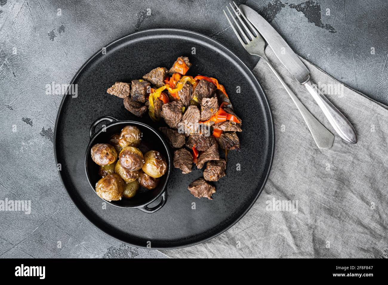 Viande de bœuf compotée de pommes de terre, carottes et épices, sur fond de pierre grise, plan de dessus Banque D'Images