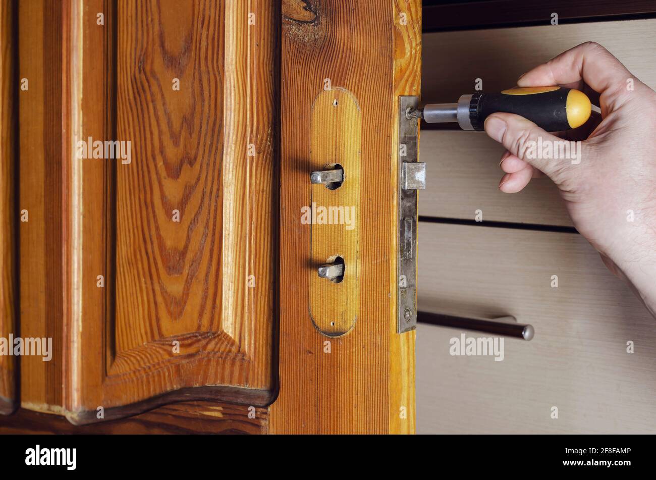 Un homme retire l'ancienne serrure de porte. À l'aide d'un tournevis,  dévissez les vis de fixation de la serrure encastrée d'une porte intérieure  en bois. Services à repai Photo Stock - Alamy