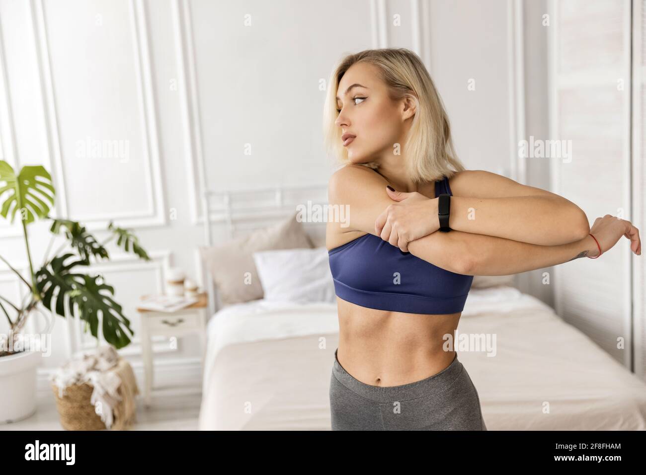 La femme sportive blonde-cheveux s'étire avant l'exercice, s'entraîner le matin à la maison. Belle jeune femme fait l'échauffement avant l'entraînement Banque D'Images