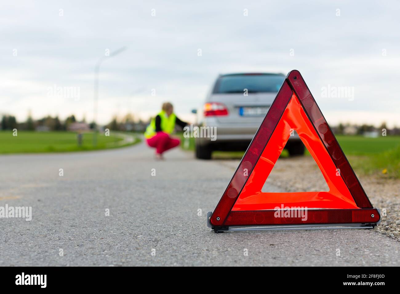 Jeune femme avec triangle de signalisation sur la rue après une panne de  voiture Photo Stock - Alamy