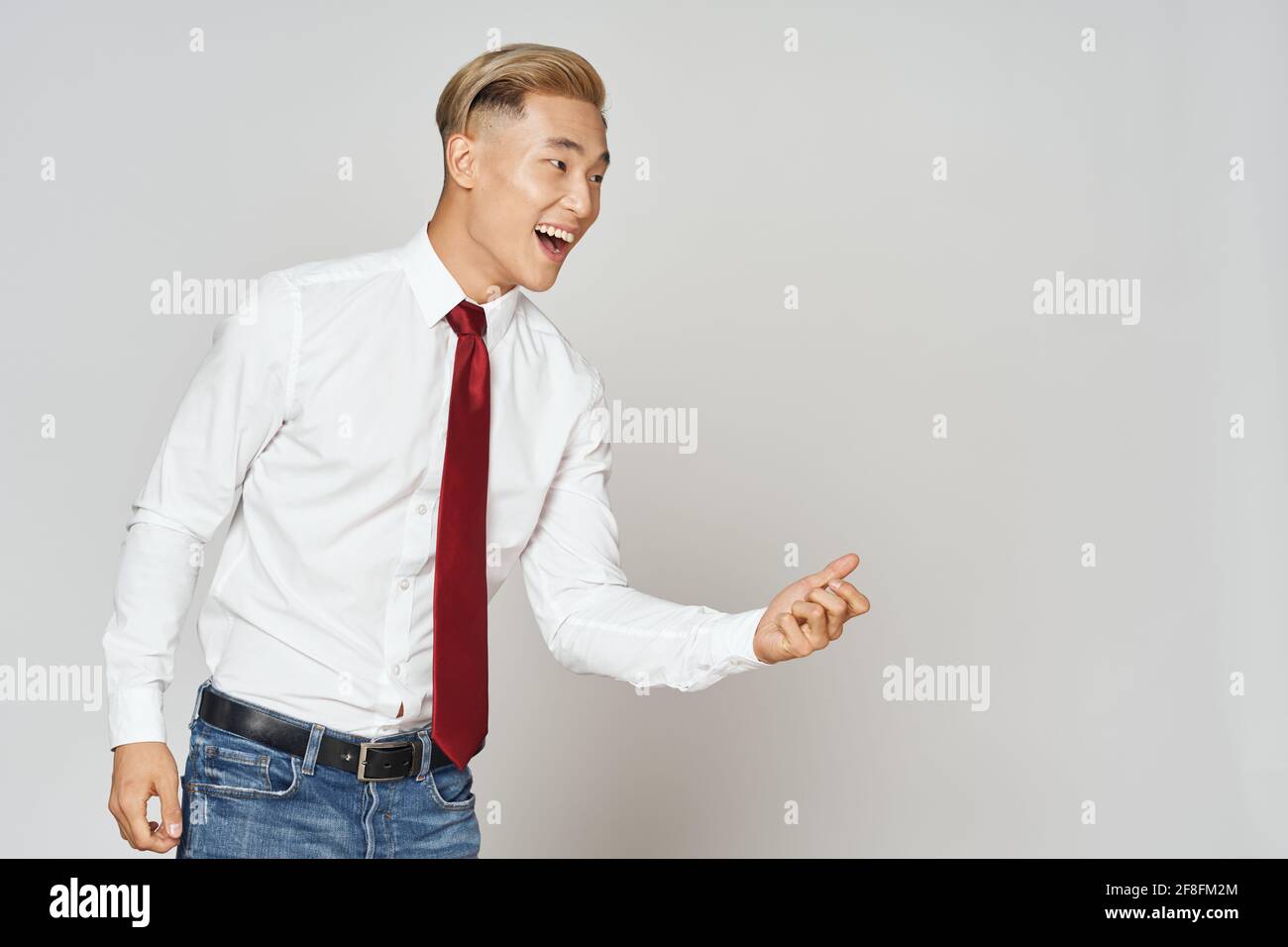 un homme dans une cravate de chemise et des gestes de jean avec ses mains et  regarde sur le côté Photo Stock - Alamy